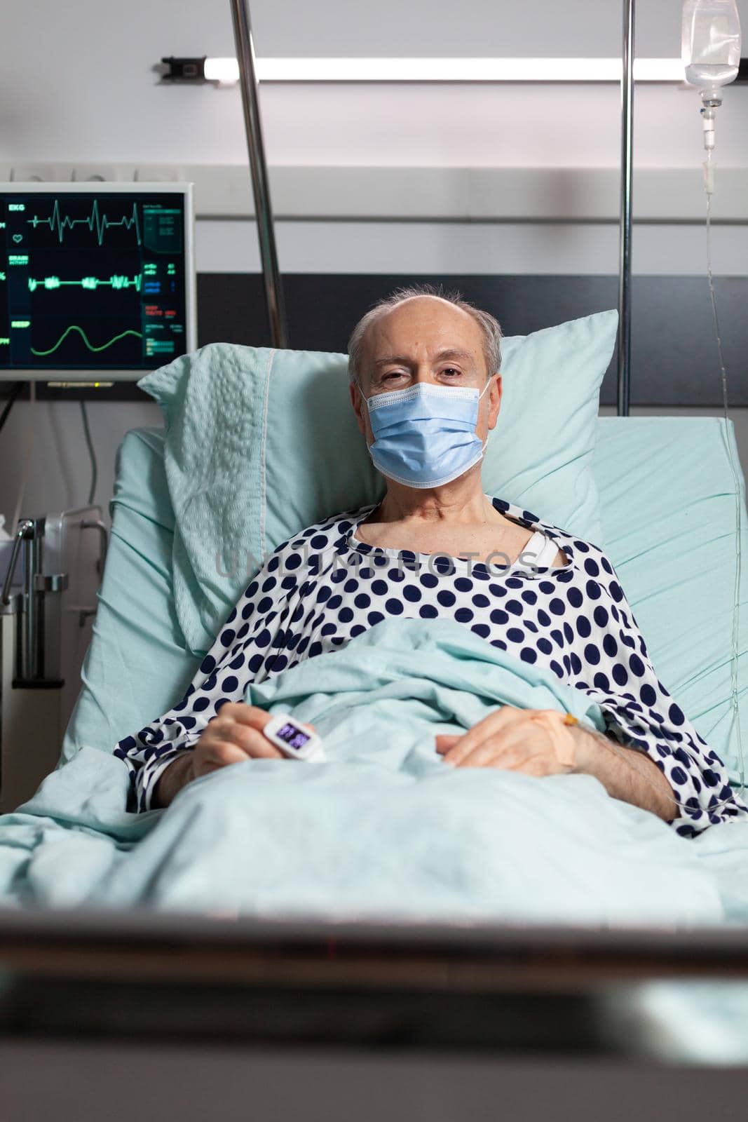 Portrait of sick senior man patient with chirurgical mask resting in hospital bed by DCStudio