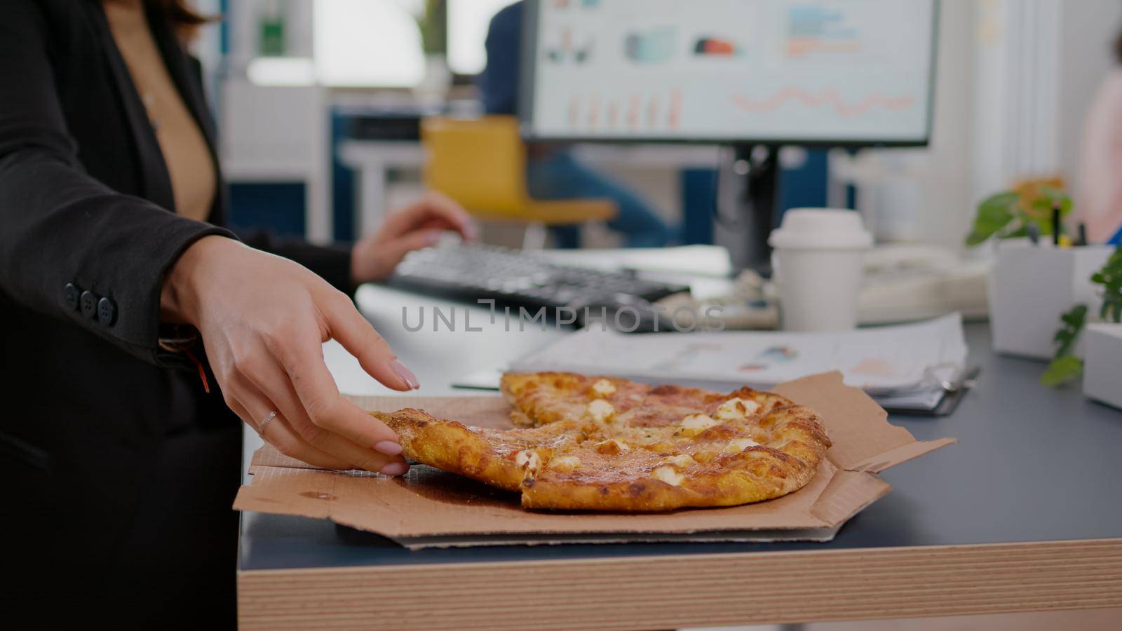 Closeup of businesswoman having fast food order takeout lunchtime working in startup company office. Executive manage taking slice of pizza. Lunch meal break package delivered at startup office.