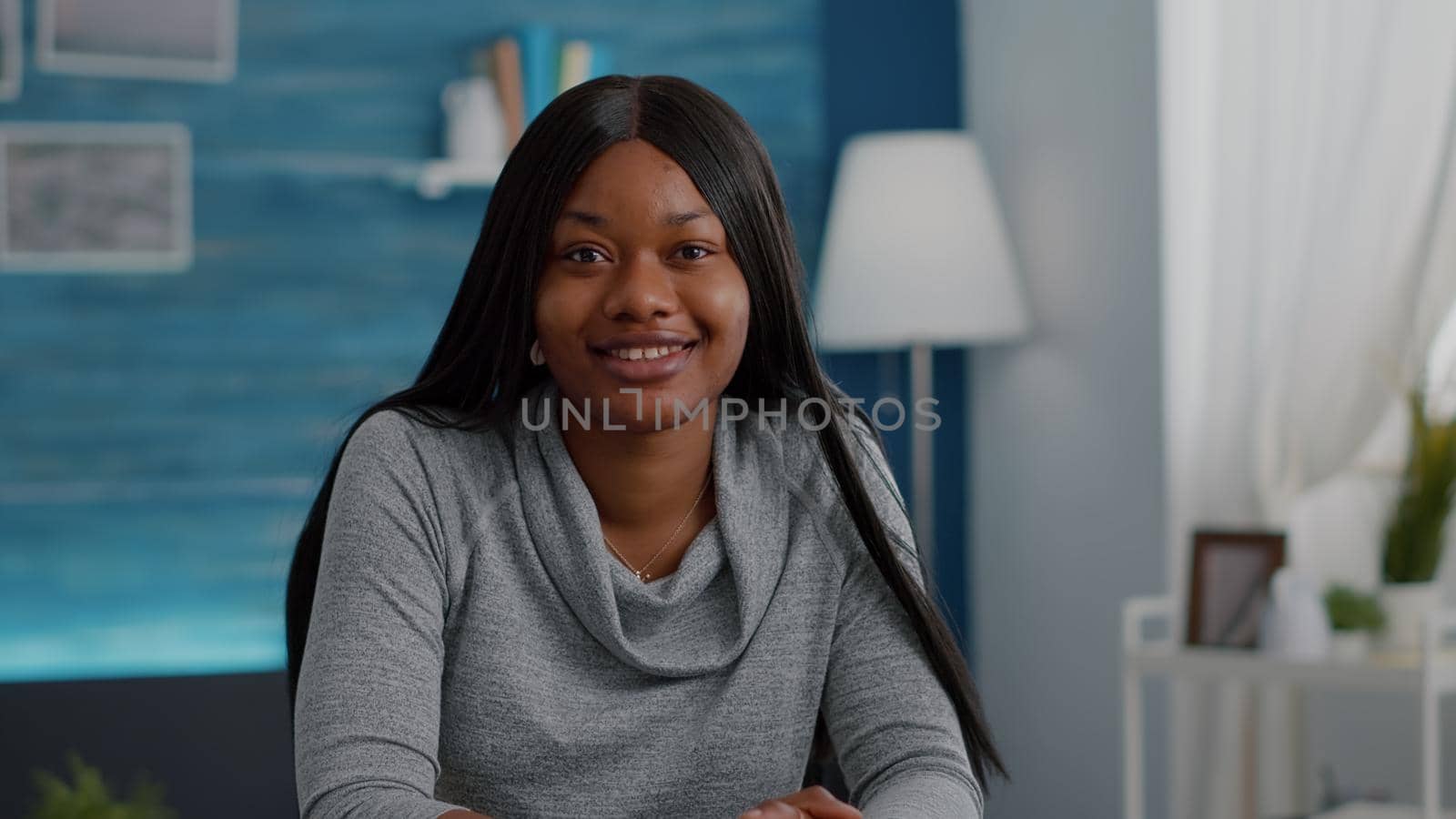 Portrait of confident student relaxing at desk table in living room looking into camera by DCStudio