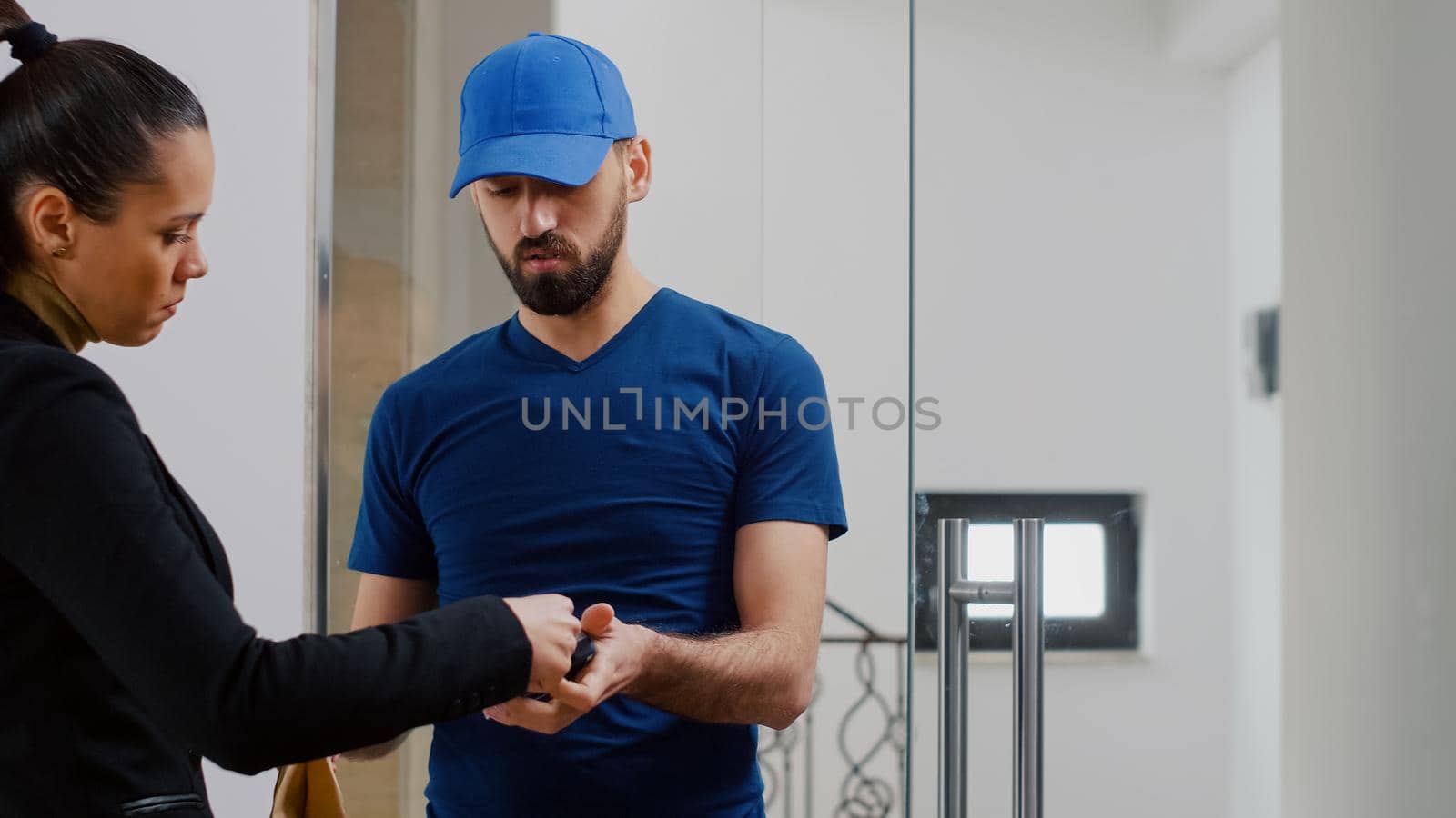 Delivery guy holding POS terminal service delivering takeaway food meal order in business company office. Businesswoman paying lunch using contactless credit card during takeout lunchtime