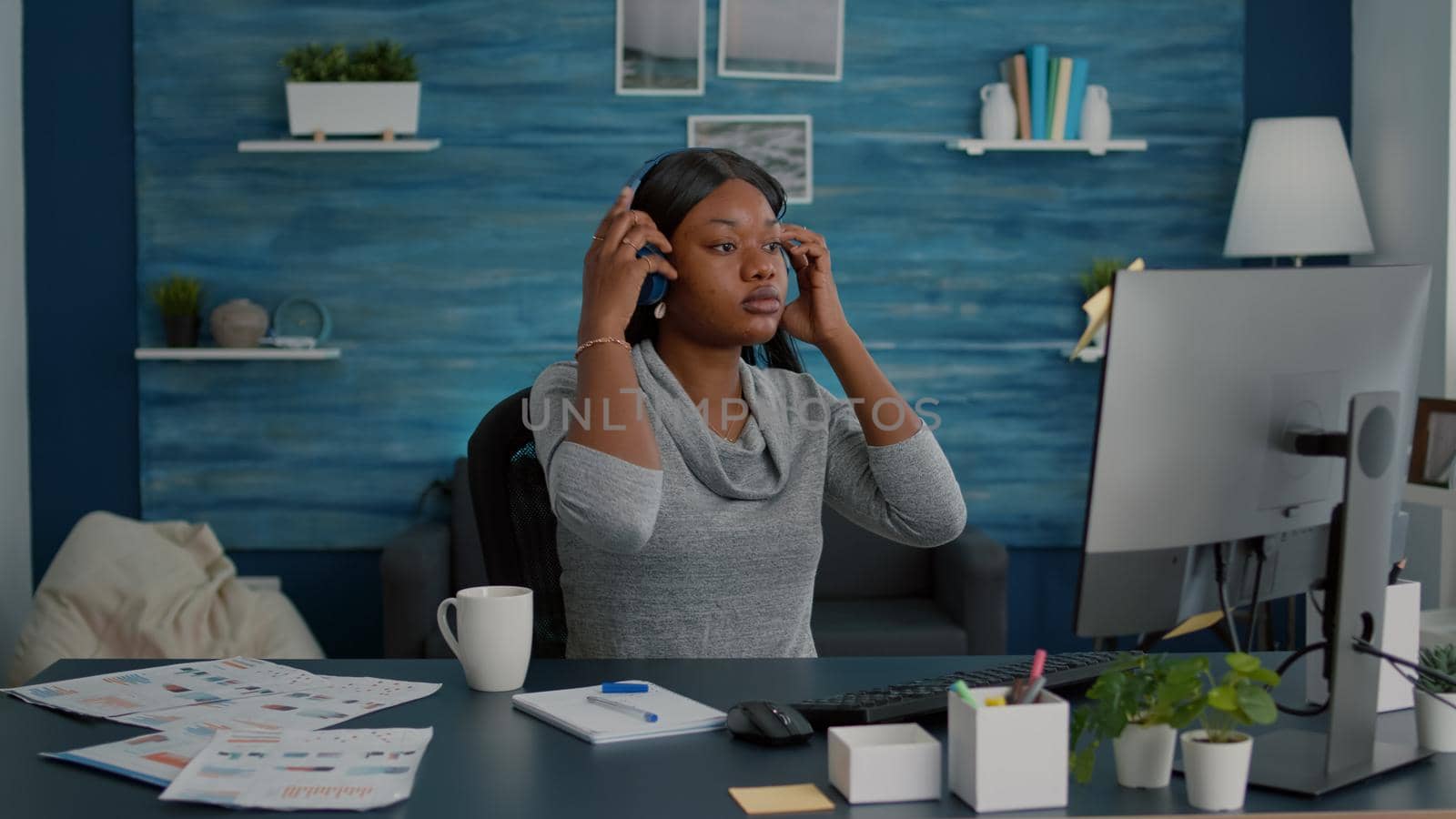 Student with black skin putting headphones listening music browsing school ideas on internet by DCStudio