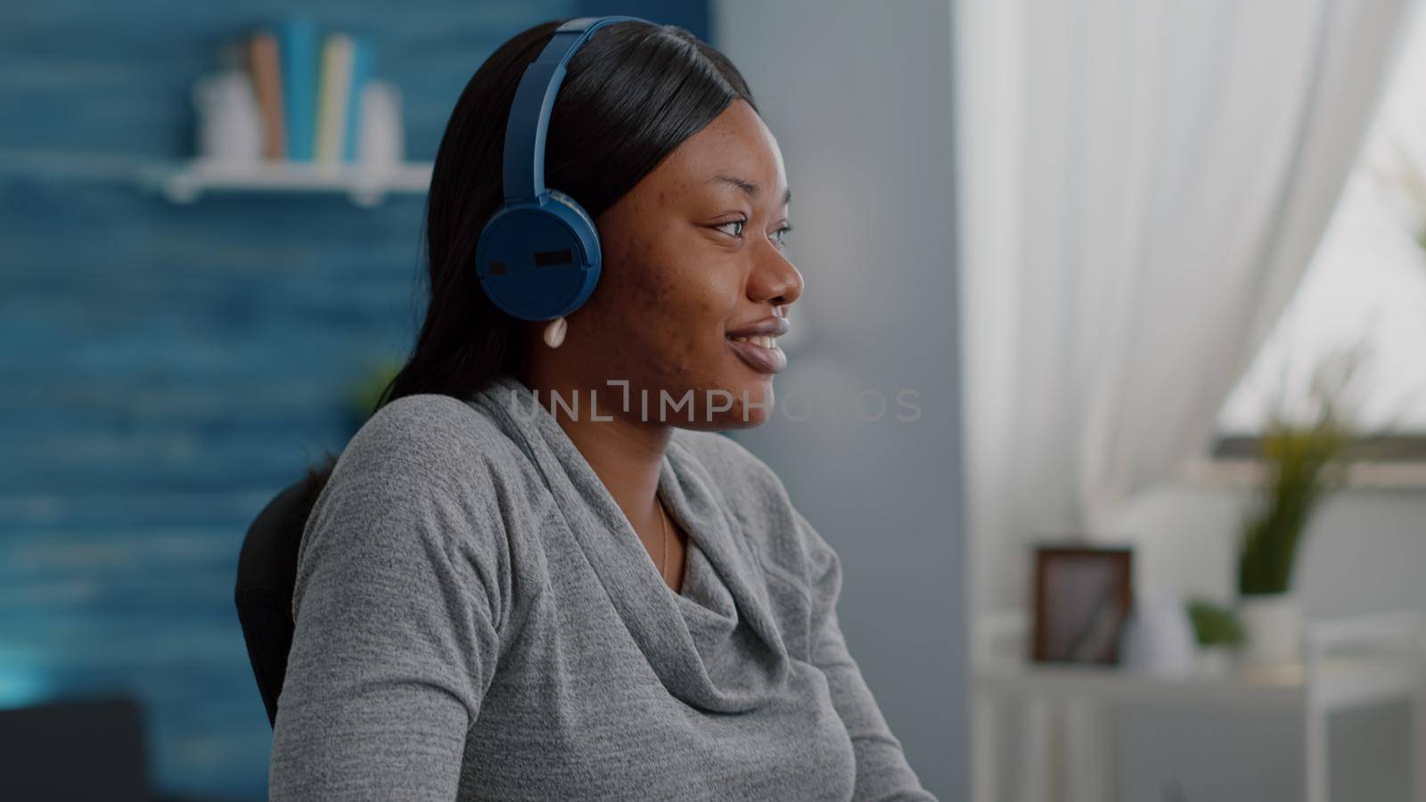African american student putting headphone on head start listening relaxing music working remote from home sitting at desk in living room. Black woman browsing online course surfing on internt