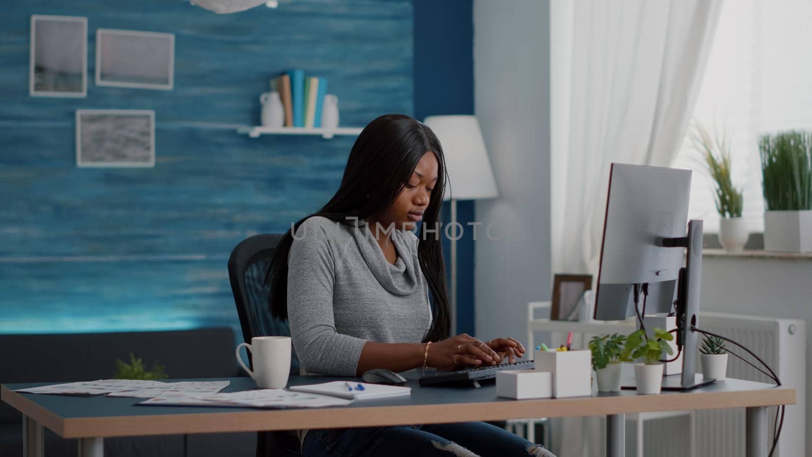 African american student sitting at desk table start typing online homework using computer by DCStudio