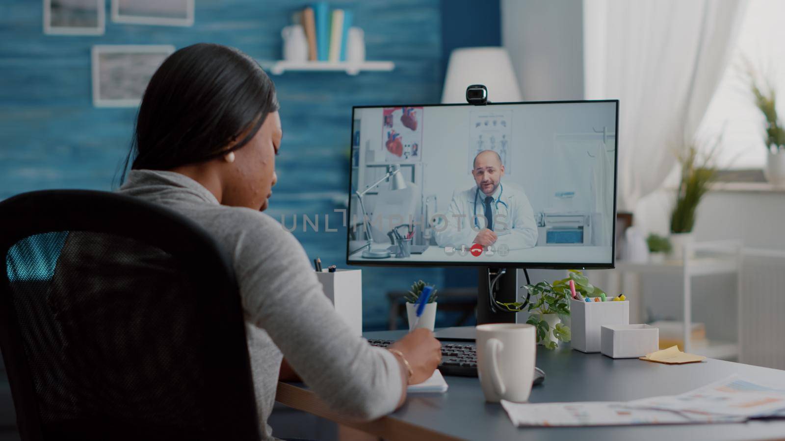 African american woman writing respiratory sickness treatment on notebook discussing pills treatment during online healthcare videocall meeting conference. Therapist doctor working remote from home