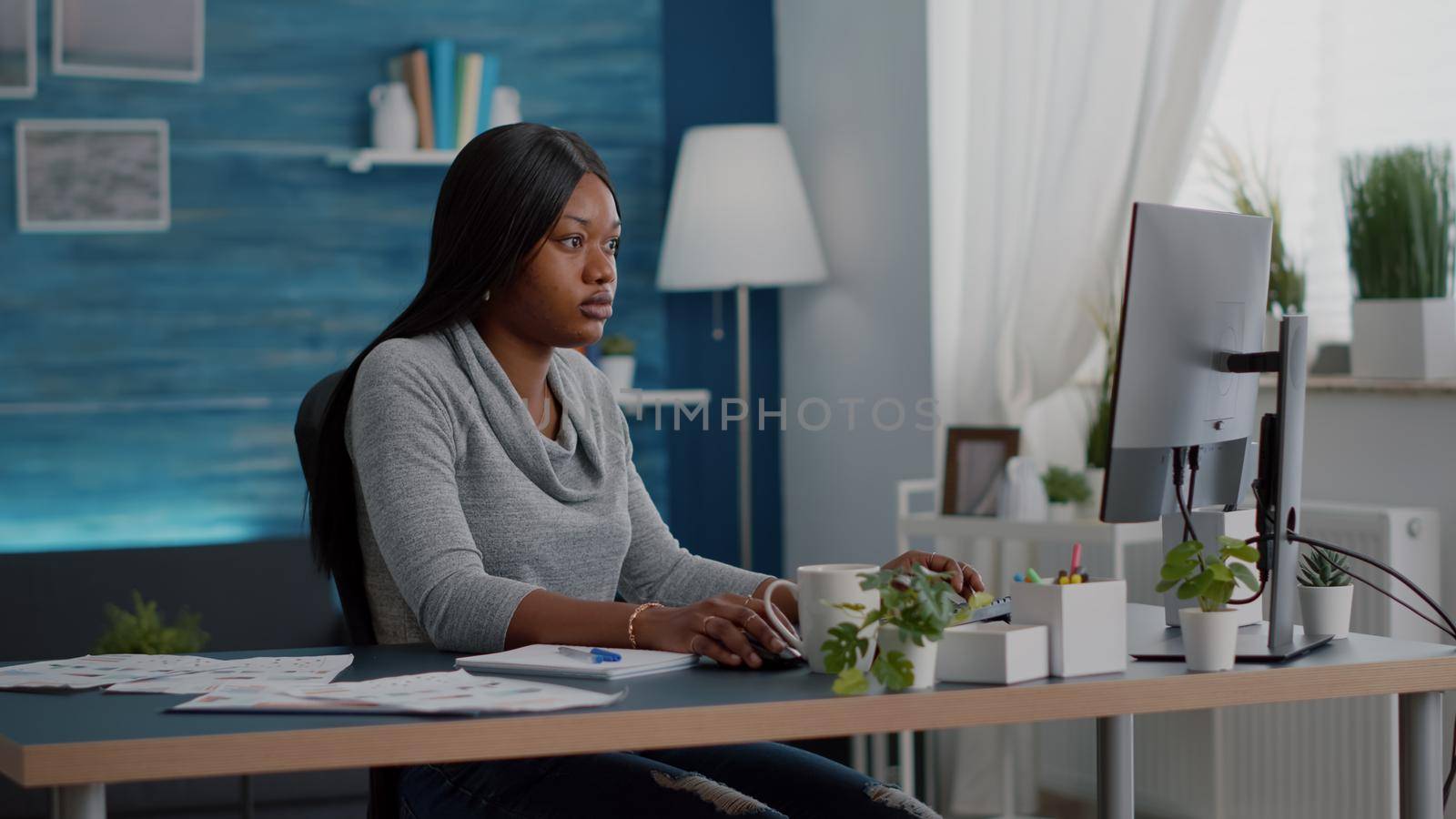 African american student with dark skin working remote from home at marketing online course using elearning university platform. Computer user sitting at desk table in living room browsing information