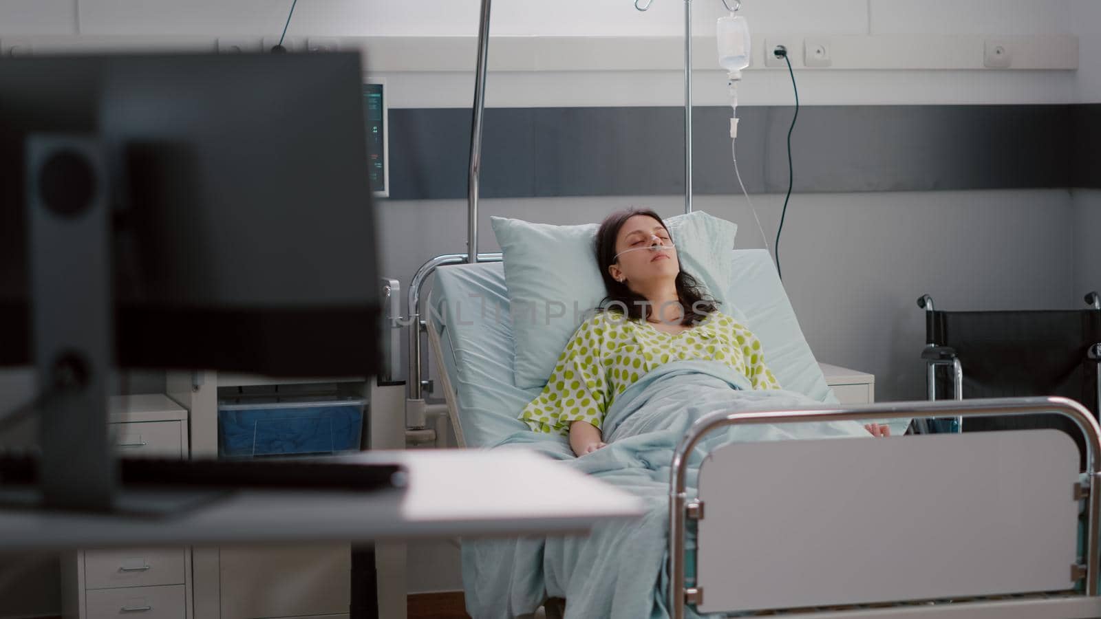 Front view of sick caucasian female falling asleep recovering after cardiology recovery in hospital ward during medical therapy. Doctors monitoring healthcare medication checking illness treatment