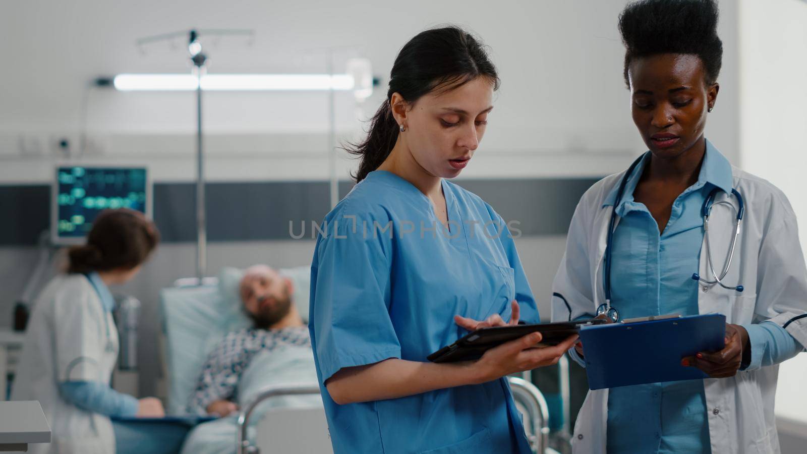 Woman nurse showing medical expertise using tablet computer to specialist black doctor woman. Hospitalized patient discussing healthcare treatment during recovery consultation