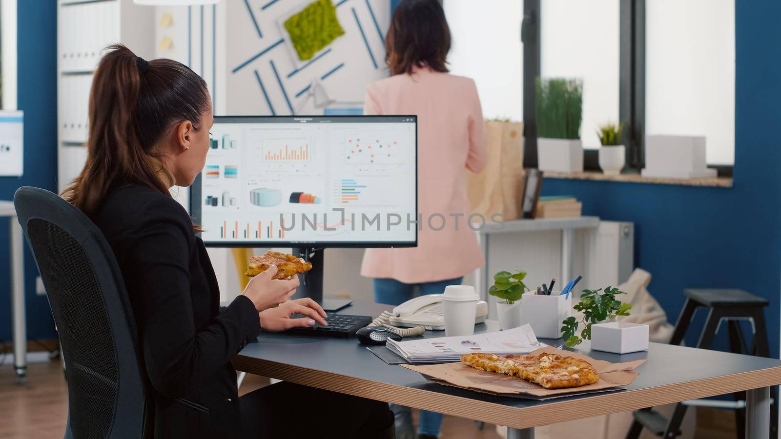 Businesswoman having lunch break sitting at table eating fastfood delivery in company office. Takeaway delivery meal order package delivered at company office. Woman eating pizza slice