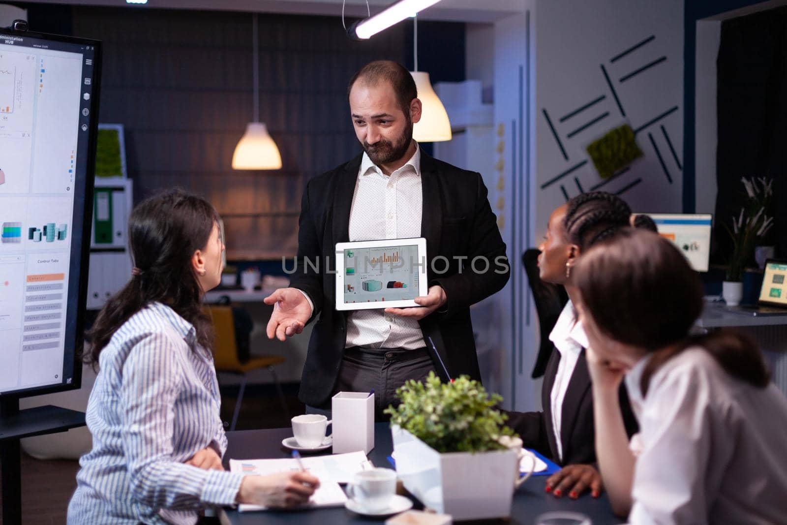 Overworked businessman showing financial graphs presentation using tablet by DCStudio