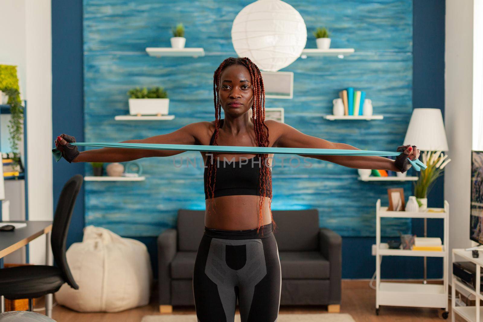 Black strong fit woman standing in living room working out by DCStudio