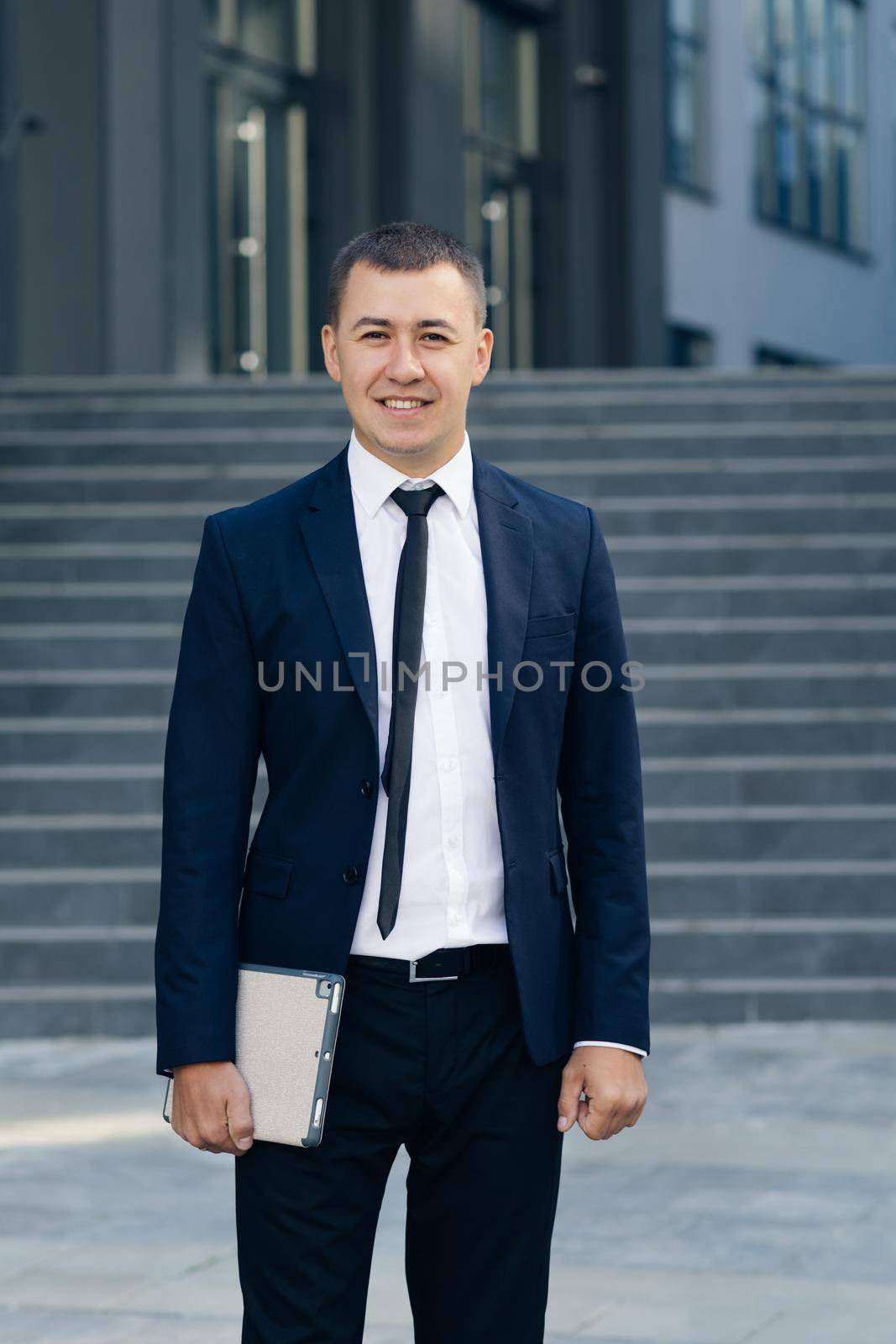 Businessman with Tablet Computer Outside Office. Thoughtful young businessman with tablet computer