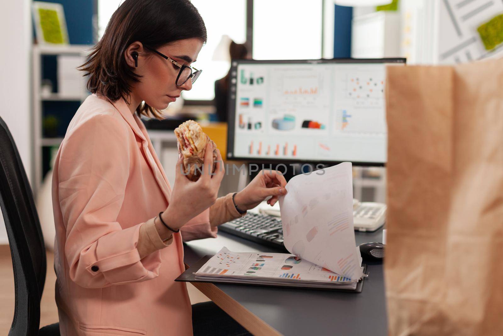 Businesswoman working in startup company office having food meal takeout lunchtime by DCStudio