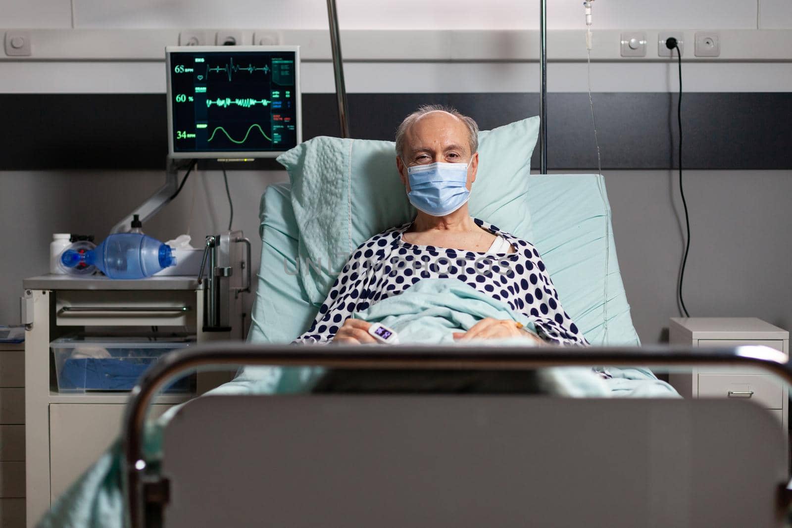 Portrait of sick senior man patient with chirurgical mask resting in hospital bed by DCStudio