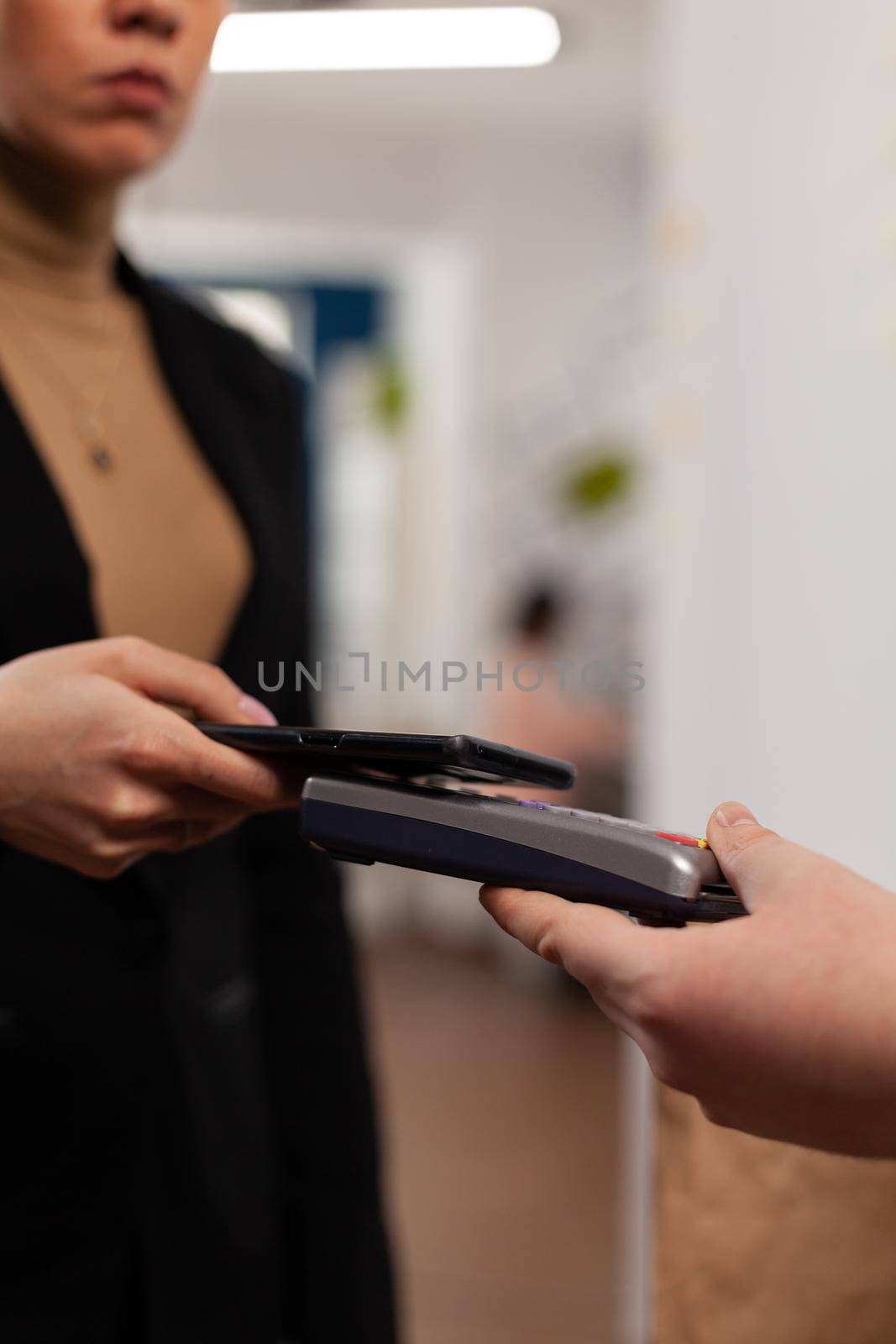 Entrepreneur using smartphone for money transaction with no card, for playing delivery guy bringing fresh tasty delicious meal lunch in paper bag. Client recieving takeaway food at workplace.