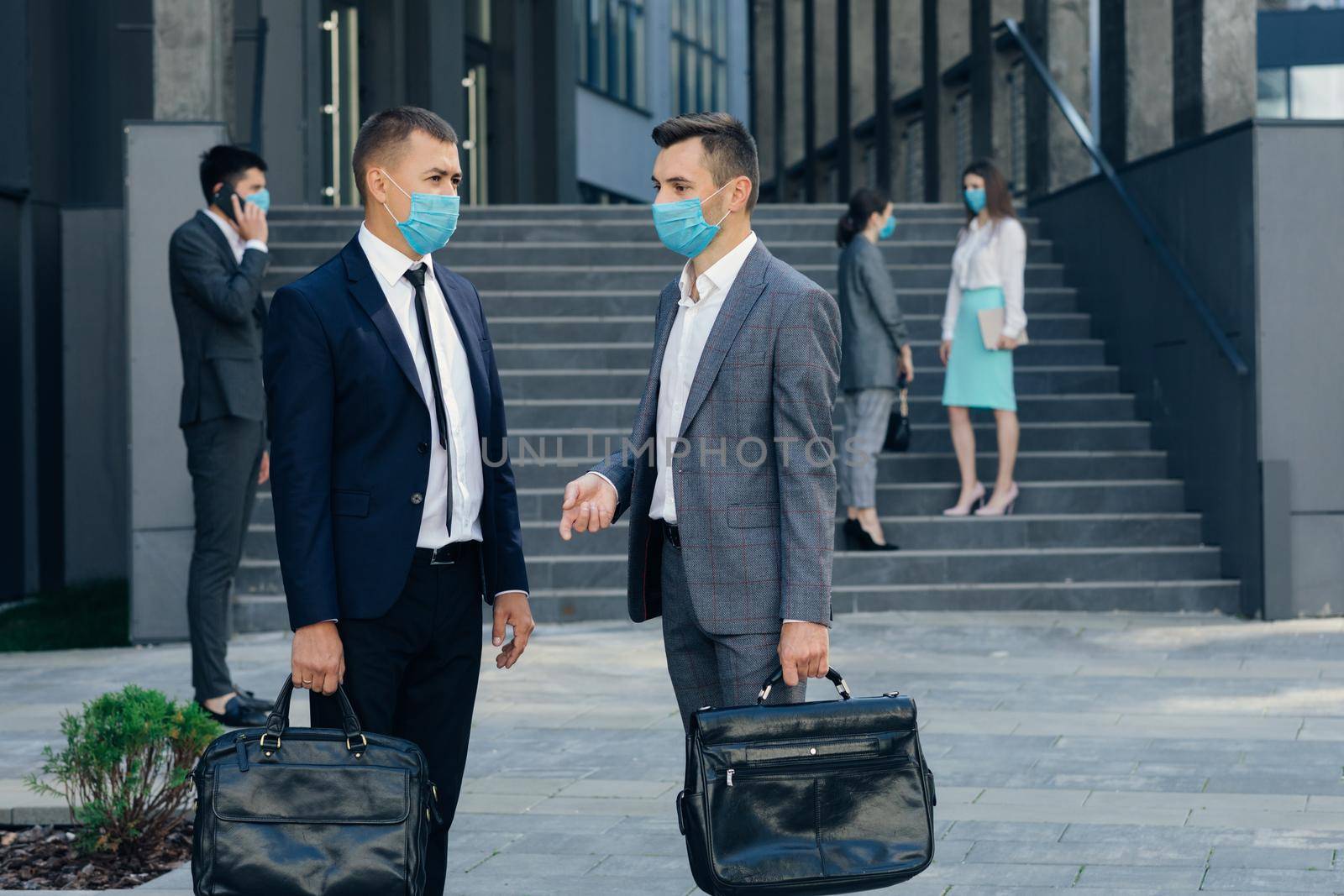 Two Business Men in Protective Mask Discussing Outside Office Building. Confident Man Explaining Something to Male Colleague