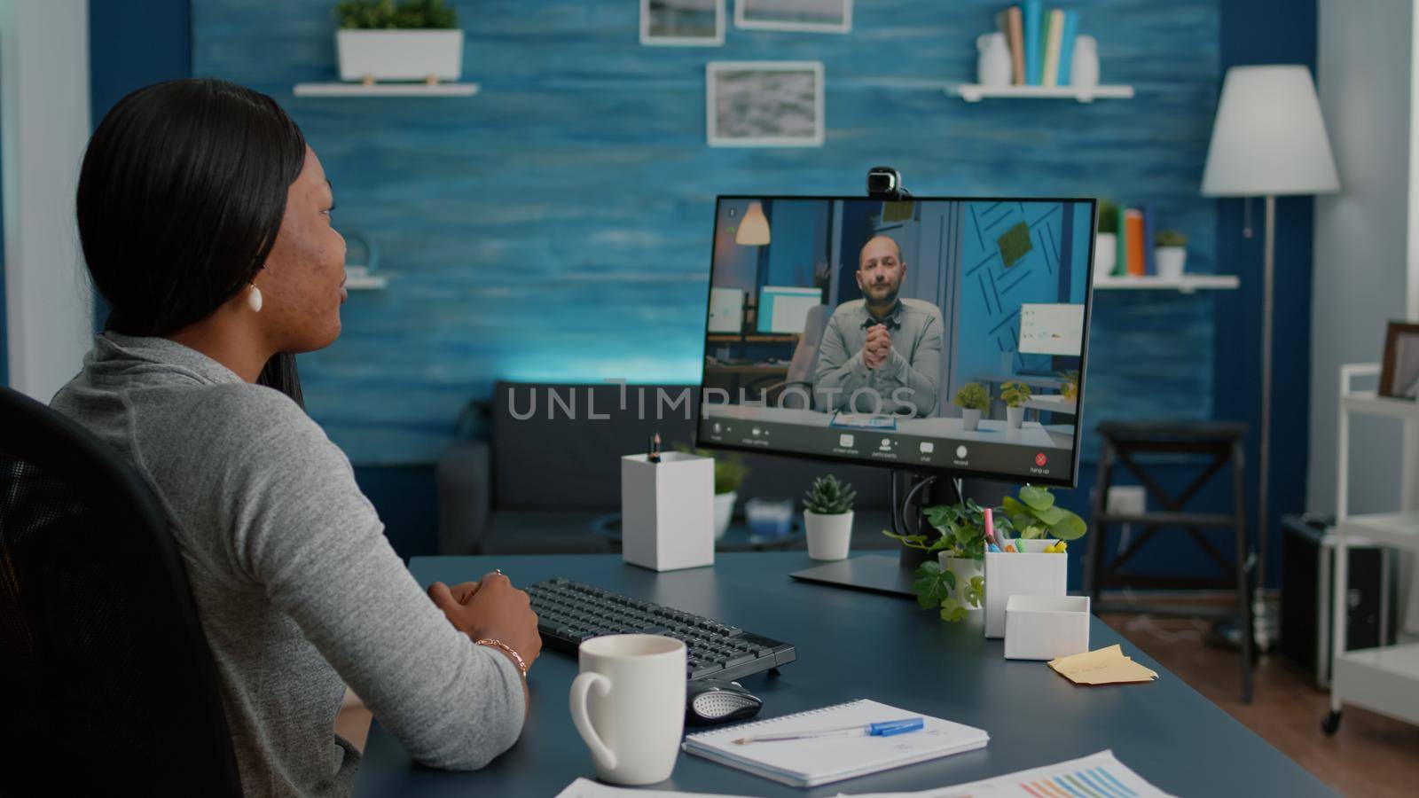 Smart black student working at marketing deadline project discussing academic ideas with entrepreneur during online videocall teleconference meeting. Woman sitting at desk using high school webinar