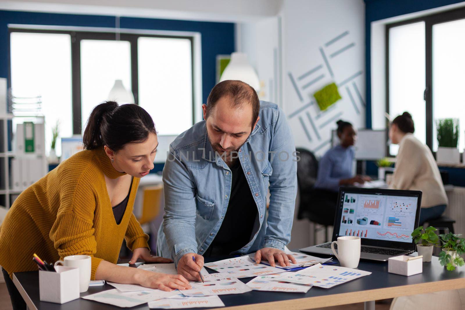 Start up multiethnic management working on charts statistics in office. Diverse team of business people analyzing company financial reports from computer.