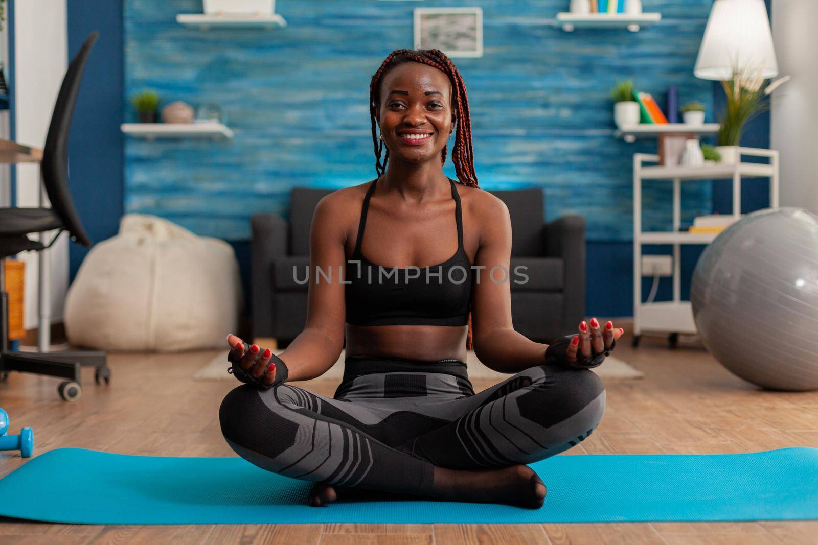 Fit black woman practicing yoga sitting with legs crossed by DCStudio