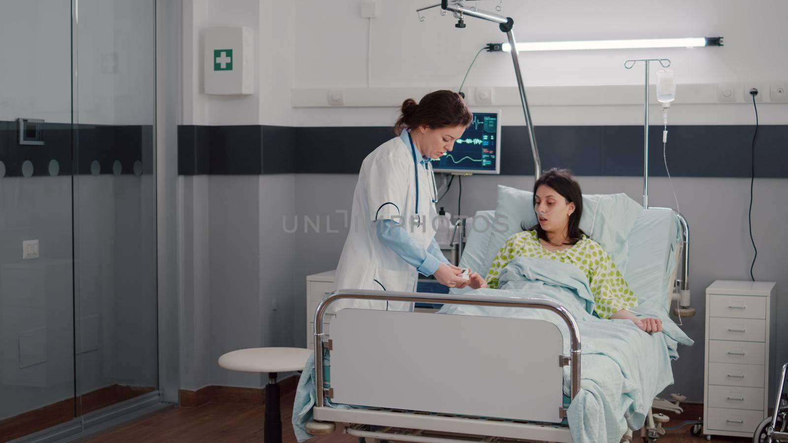 Woman doctor monitoring sick woman during rehabilitation appointment in hospital ward putting oximeter checking sickness expertise. Patient resting in bed waiting disease treatment