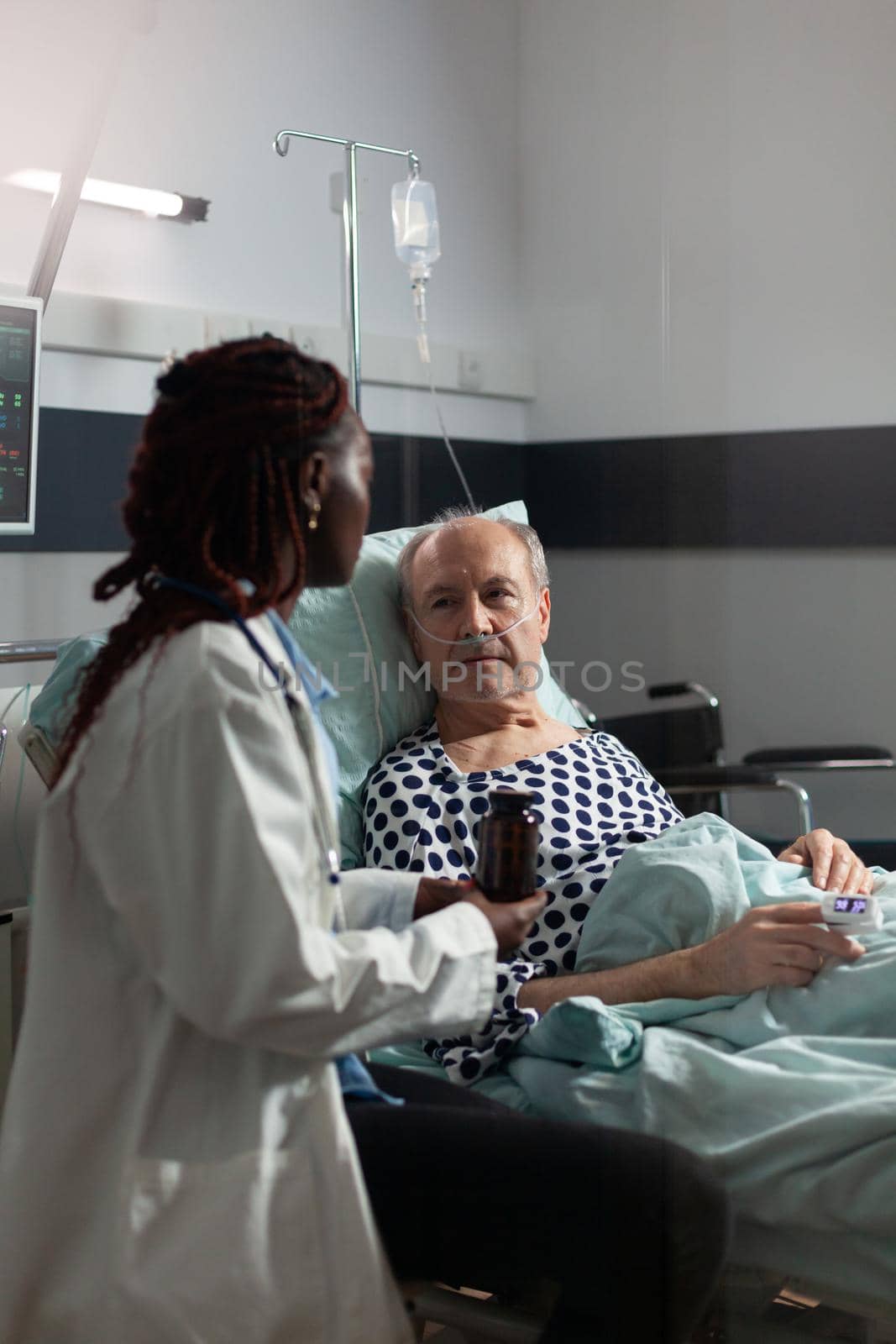 African american therapist in hospital room discussing treatment by DCStudio