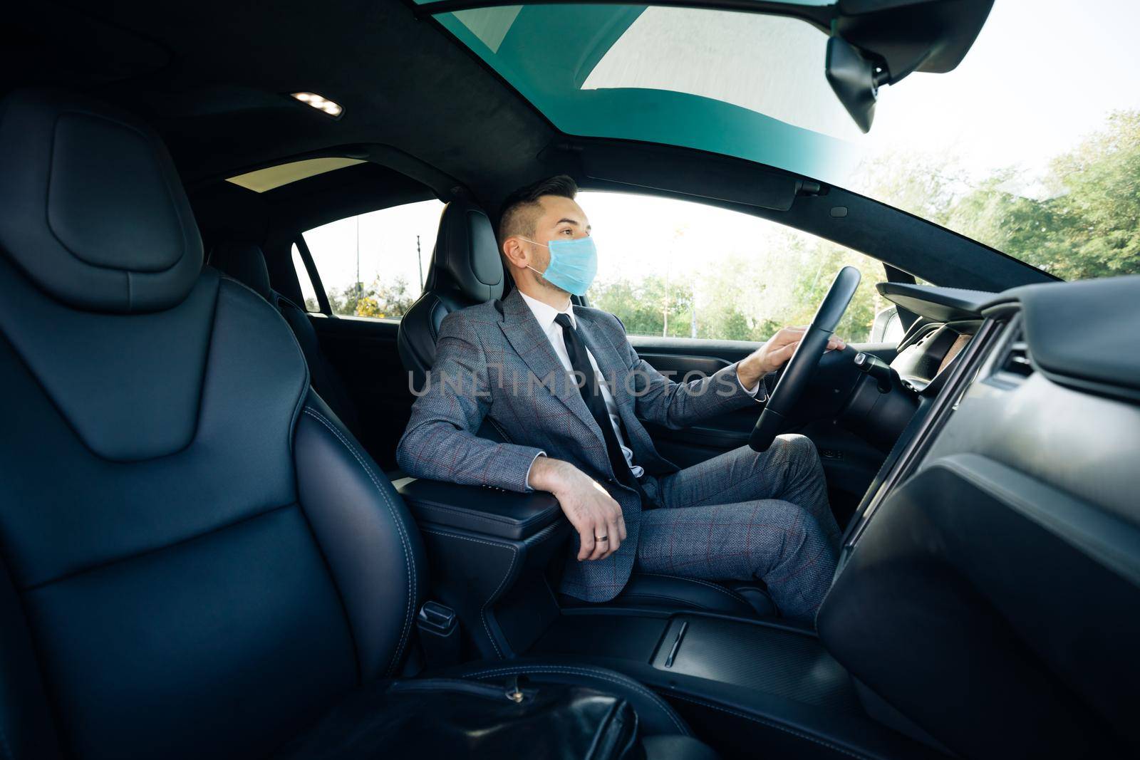 Businessman wearing medical mask in prevention for coronavirus and driving his car to work. Pandemic. Citizens. Lockdown safety. Businessman healthcare.