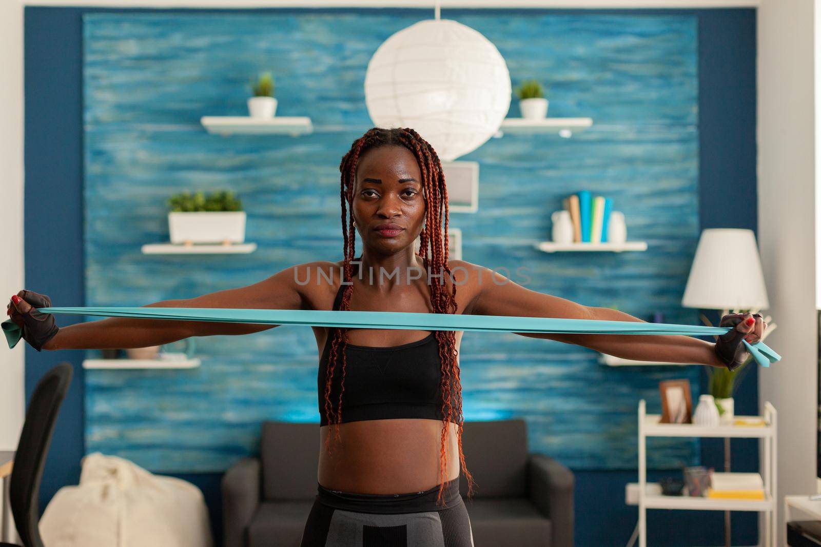 Black woman exercising muscle strength with rubber band by DCStudio