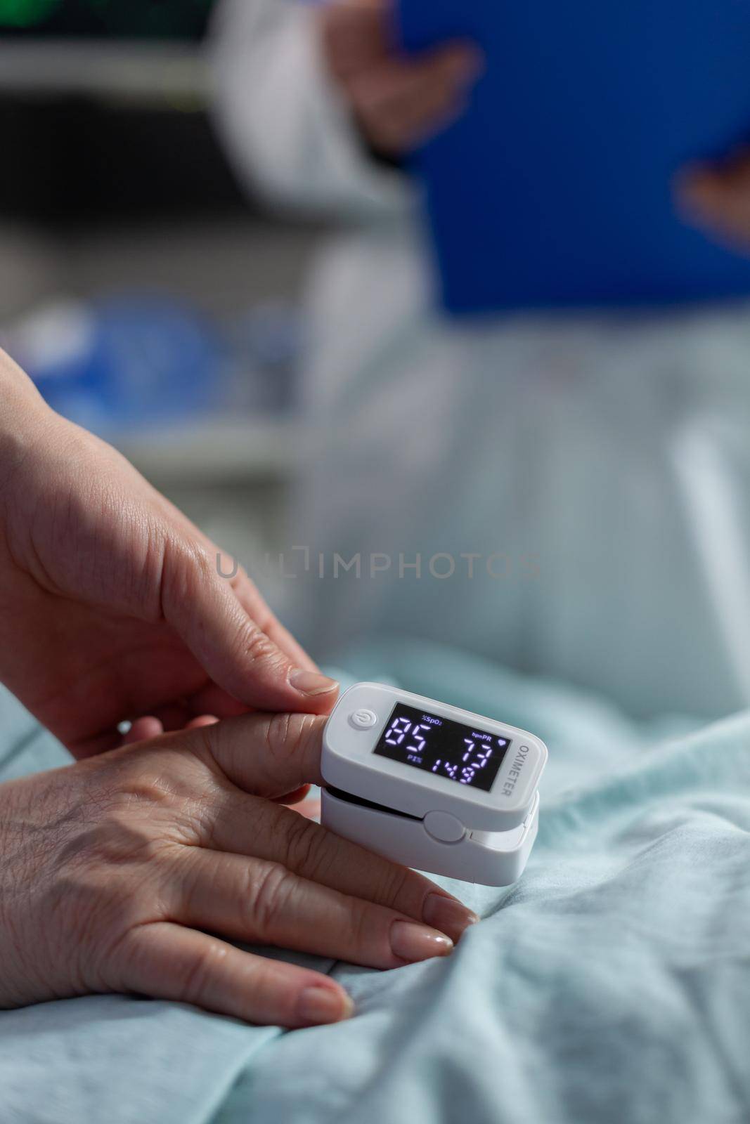 Close up of oxymeter attached on patient laying in hospital bed, indicating oxygen saturation level, pulse. Modern equipment for monitoring sick for therapy.