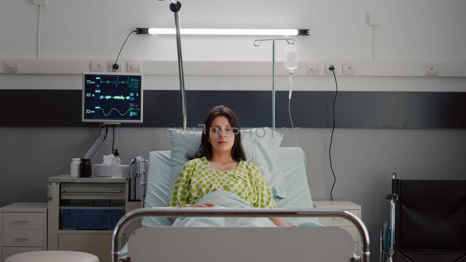 Patient wearing with nasal oxygen tube looking into camera sitting in bed by DCStudio