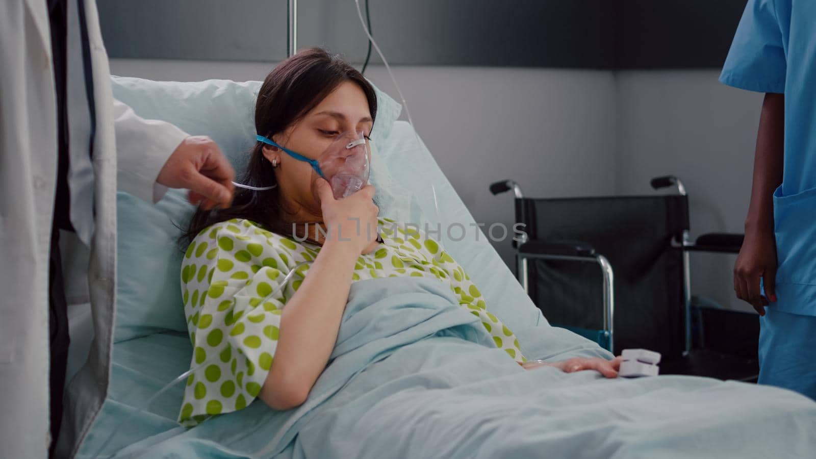 Patient resting in bed having respiratory illness while doctors monitoring heart pulse by DCStudio