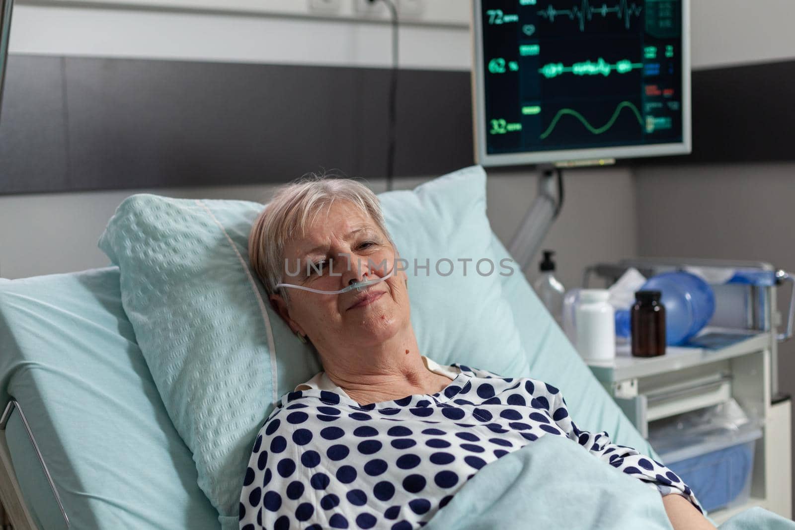 Senior elderly person with pulmonary failure breathing with help from oxygen mask, laying in hospital bed, getting treatment through iv drip bag. Patient bmp on monitor.