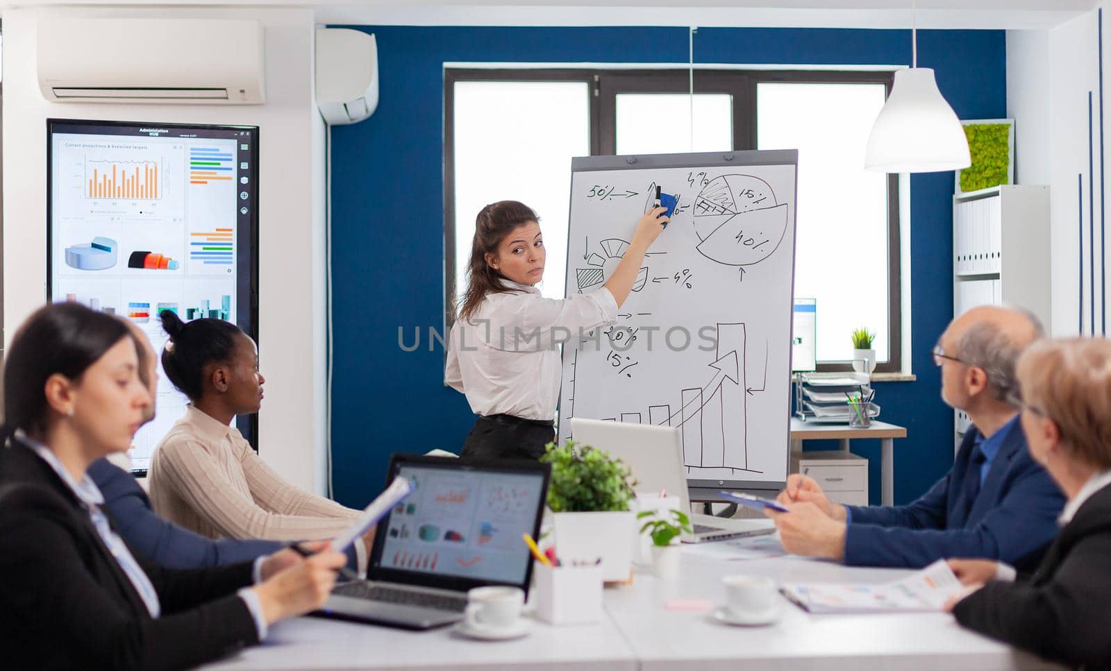 Company advisor making presentation using charts to staff by DCStudio