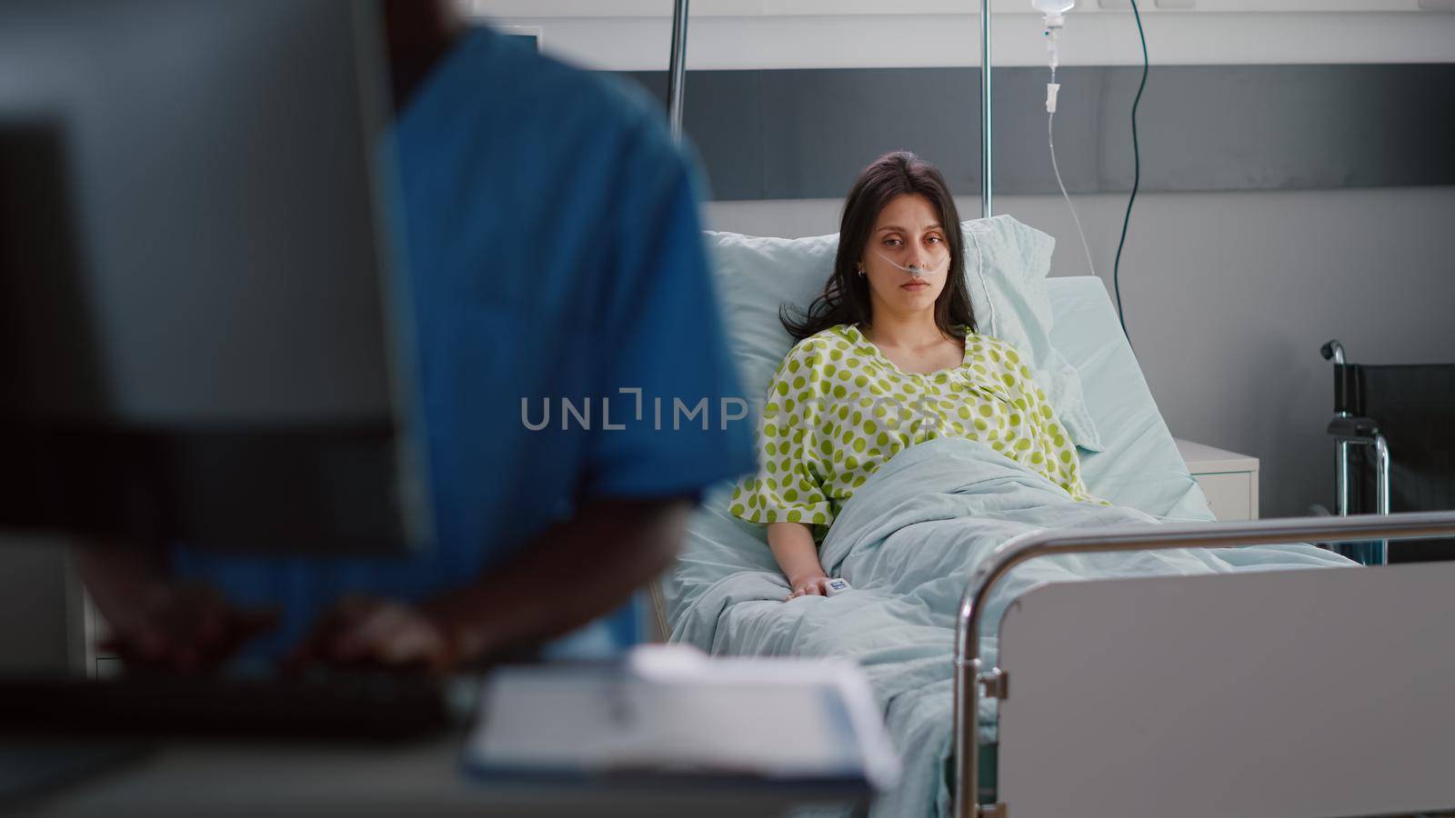 Front view of sick woman with nasal oxygen tube sitting in bed recovering by DCStudio