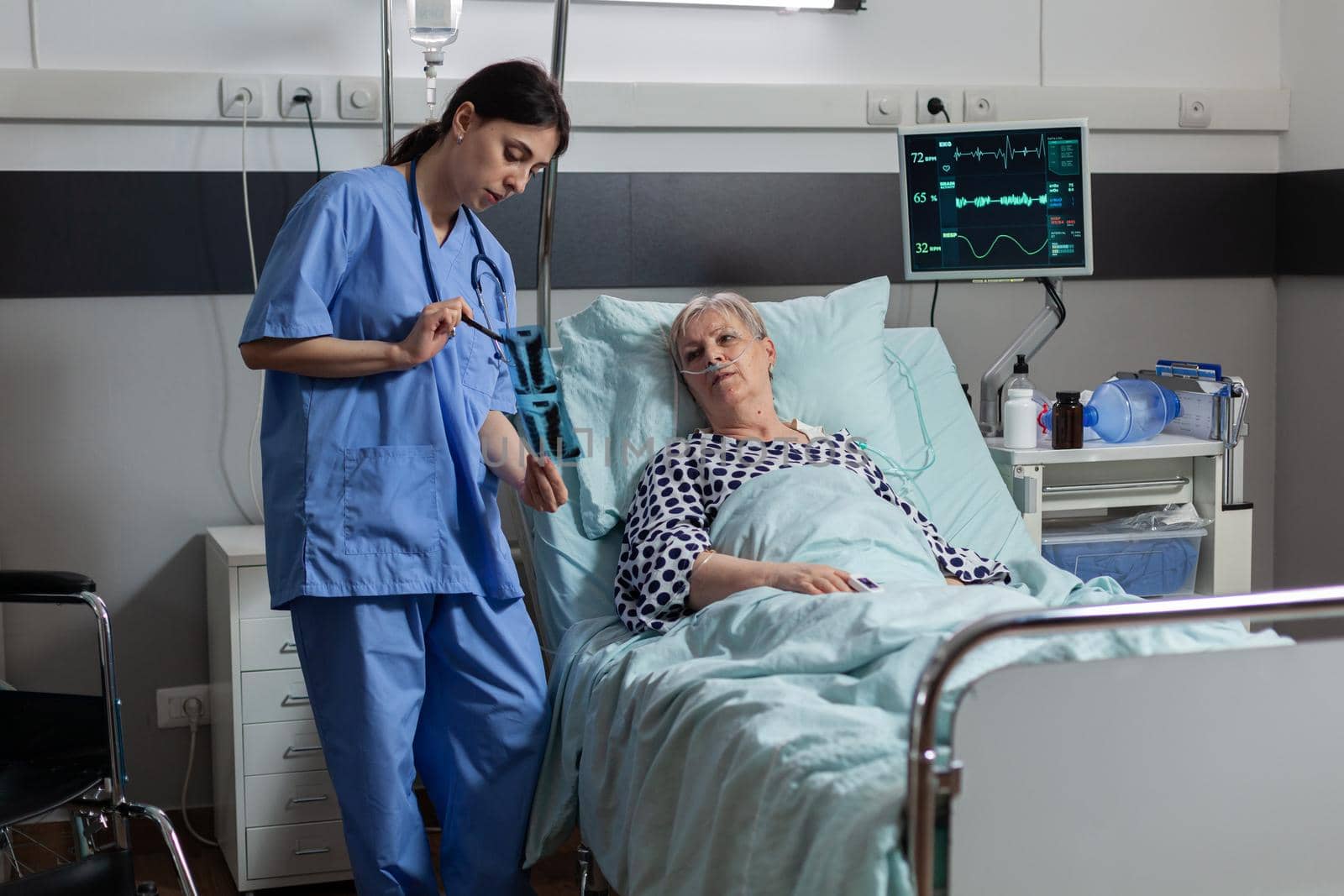 Medical nurse analyzing senior patient chest x-ray in hospital room by DCStudio