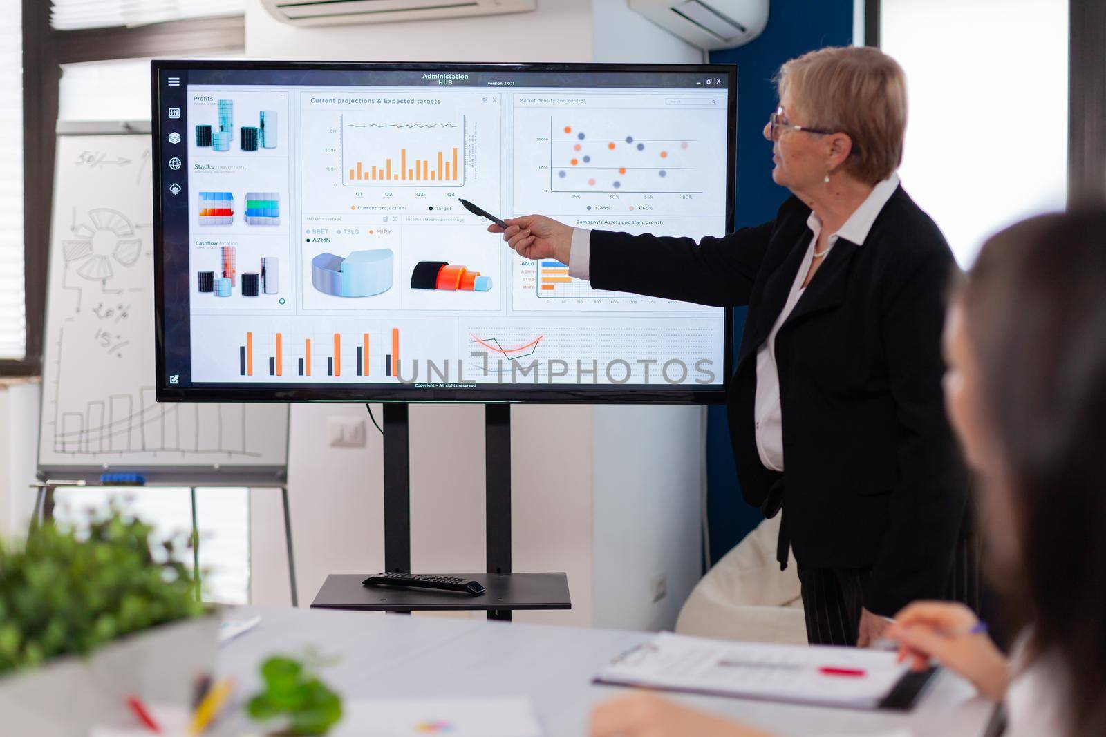 Businesswoman gives talk and speaking in conference room pointing at charts briefing. Corporate staff discussing new business application with colleagues looking at screen