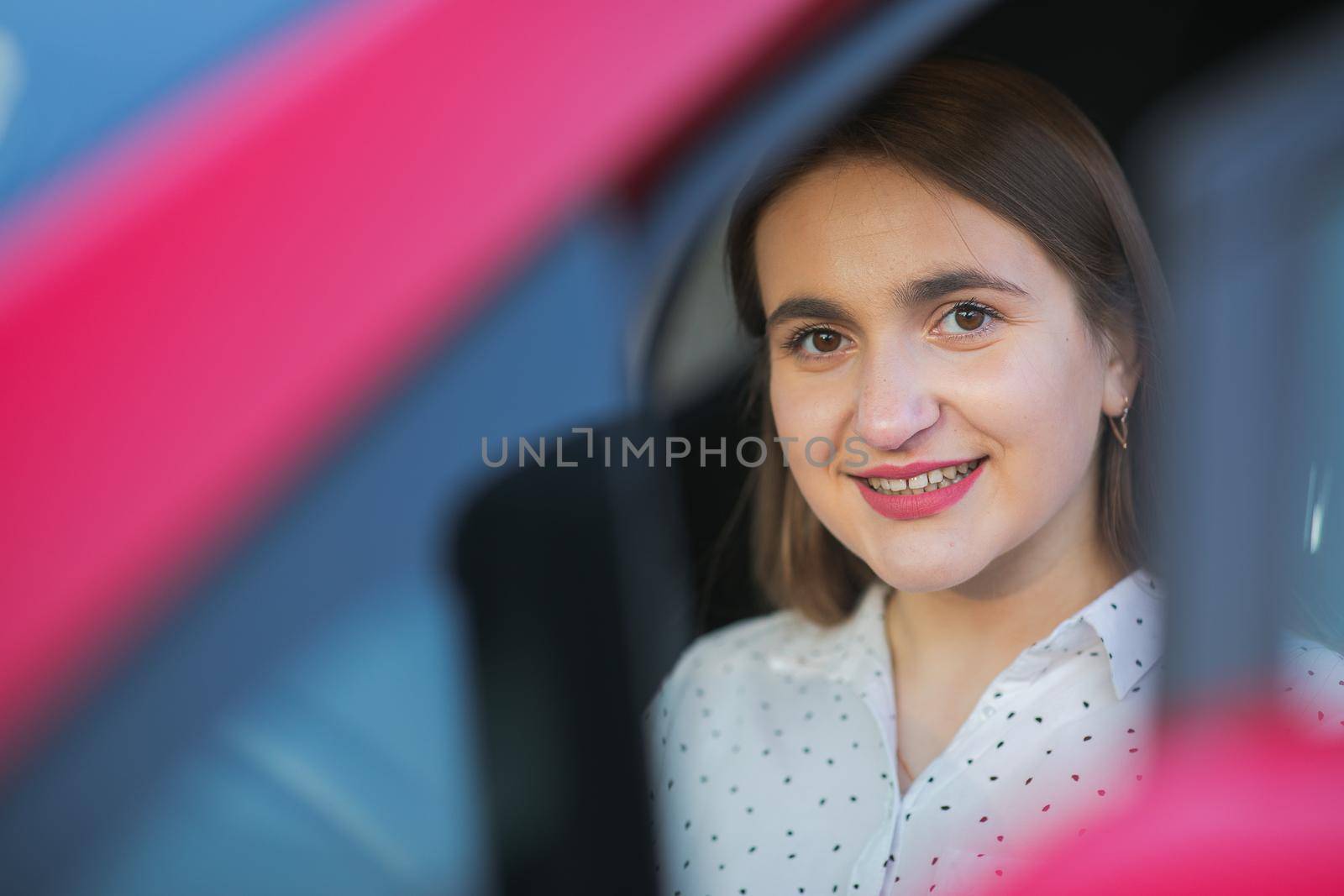 Portrait of Caucasian woman looking through car window to the camera and smiling