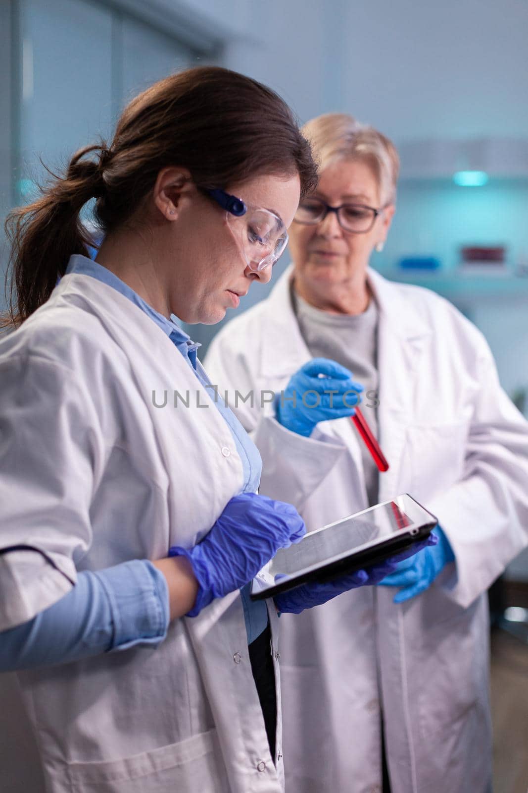 Doctors chemist researchers in white coat analysing blood test tube in equipped laboratory . Modern laboratory for scientific research with professional equipment for virus investigation working at vaccine development
