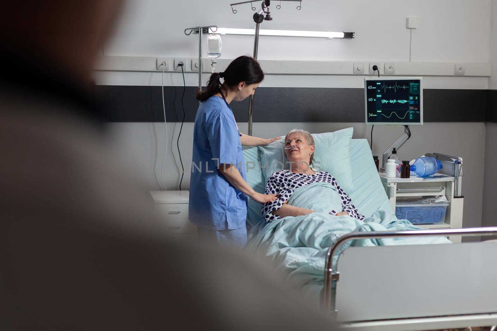 Fiendly doctor hands holding patient hand, in hospital room giving encouragement, empathy, support during medical examination. Patient breathing through oxygen mask.