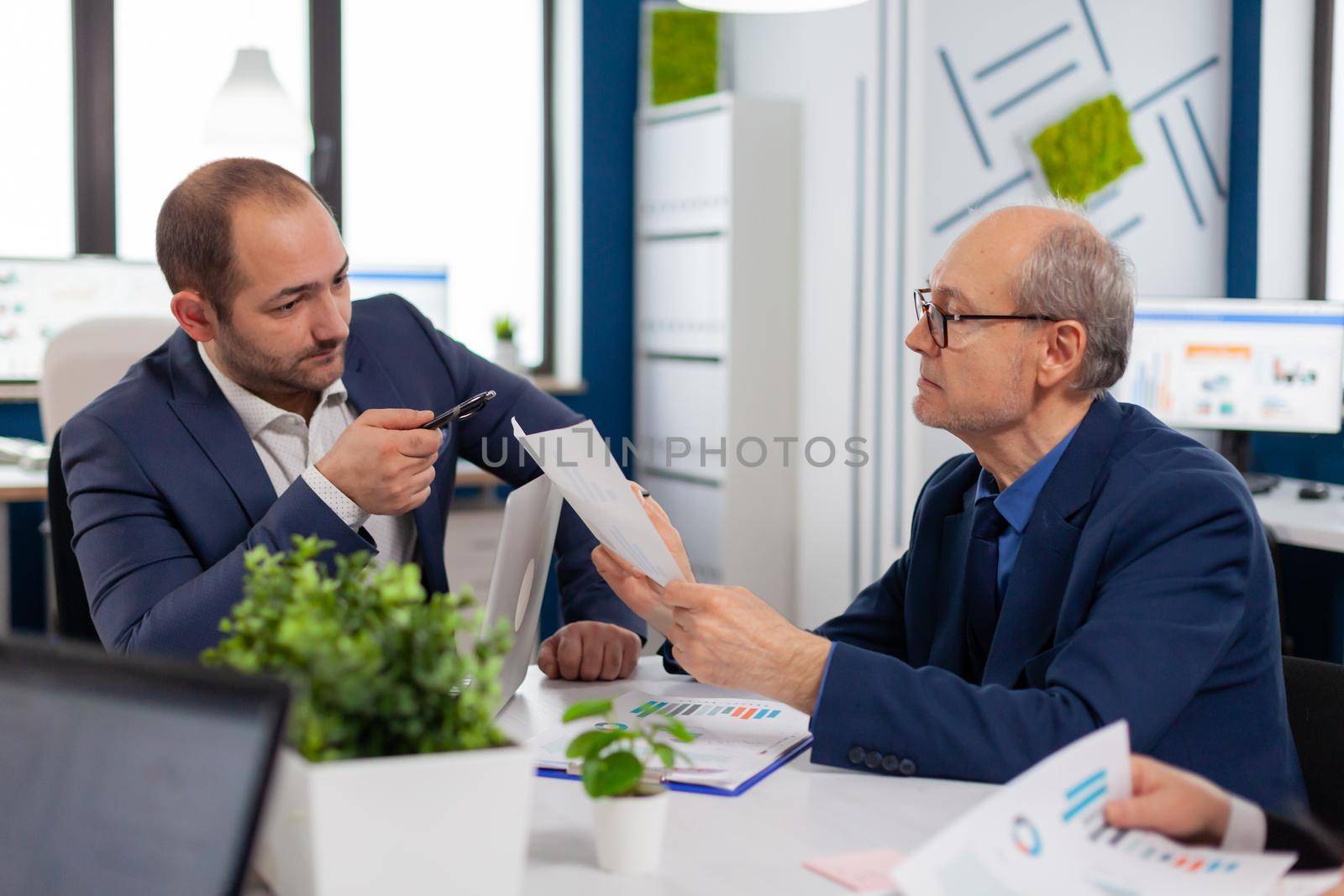 Senior entrepreneur discussing with coworker by DCStudio