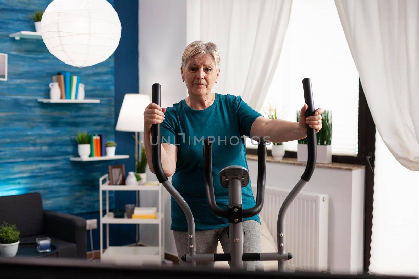 Active retirement senior woman working legs muscle using cycling bicycle machine by DCStudio