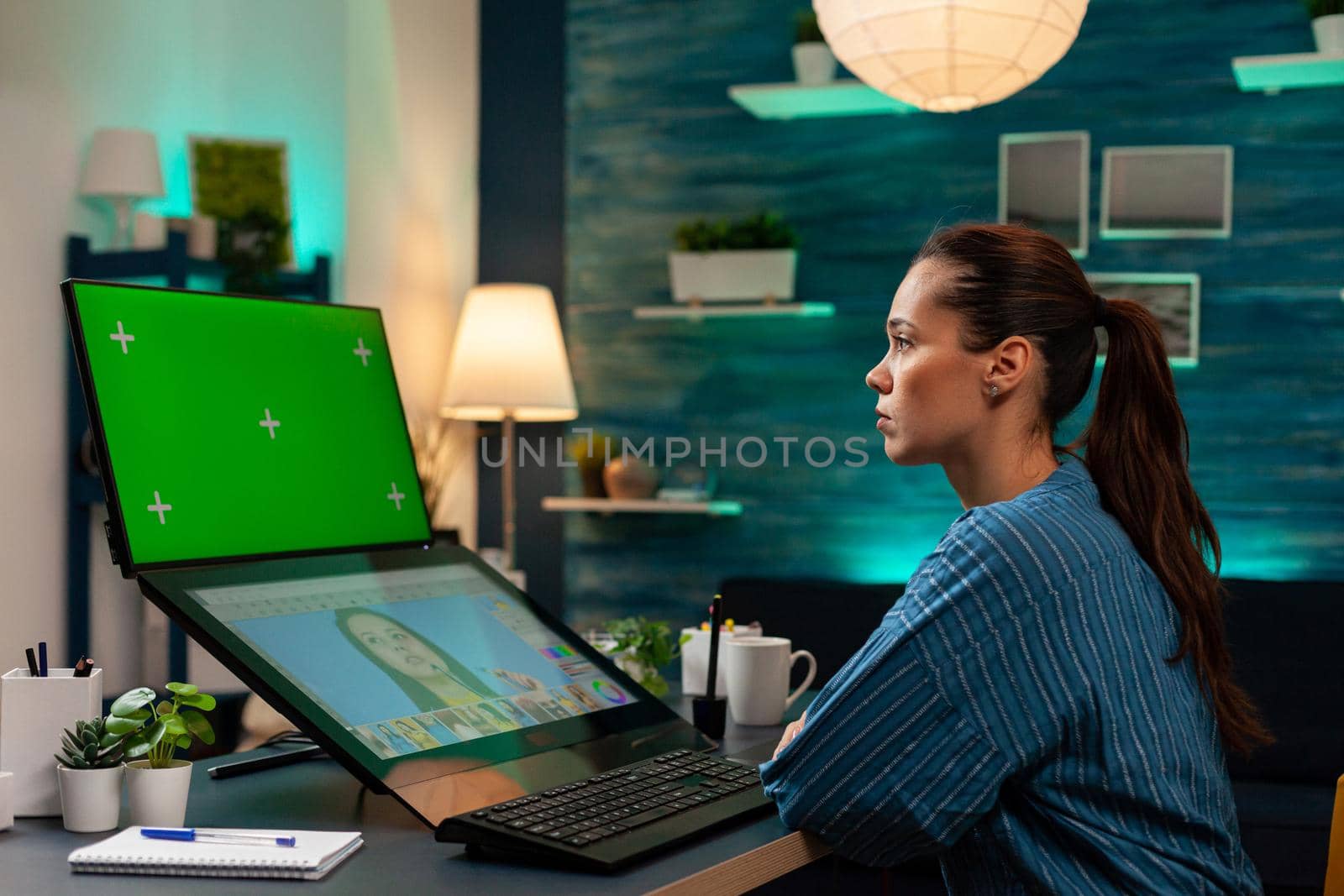 Studio editor worker looking at green screen on monitor and editing portrait picture with graphic tools. Woman photographer using chroma key mockup template for digital background display