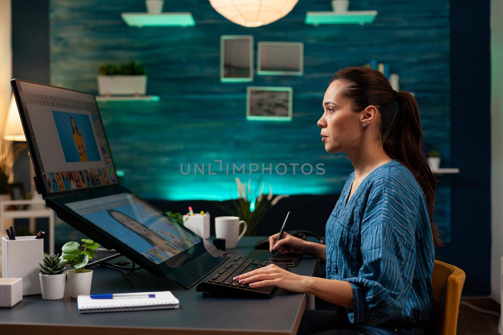 Photo editing specialist doing editor work with picture on computer display at artistic studio. Photographer woman retouching gradient on photo while using touchpad and stylus as tools