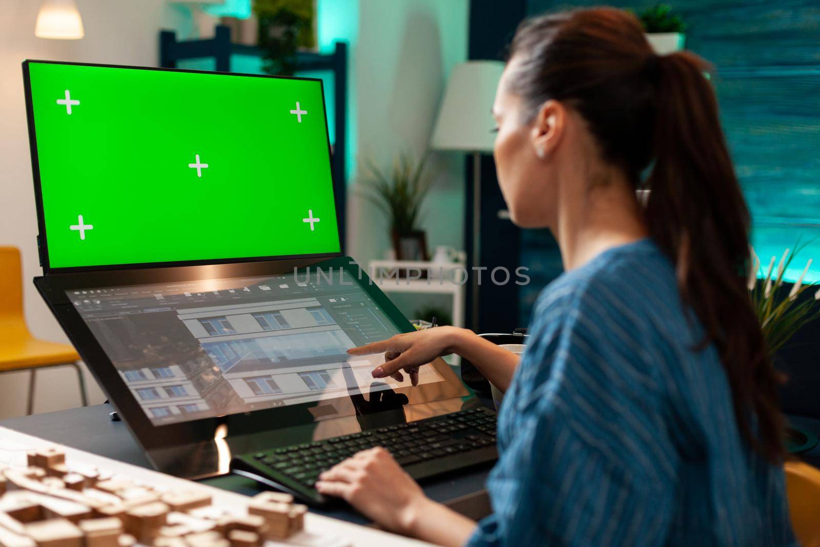 Tehnician woman working on touchpad monitor for design using green screen chroma key mockup isolated background and building plan. Construction expert doing development innovation model