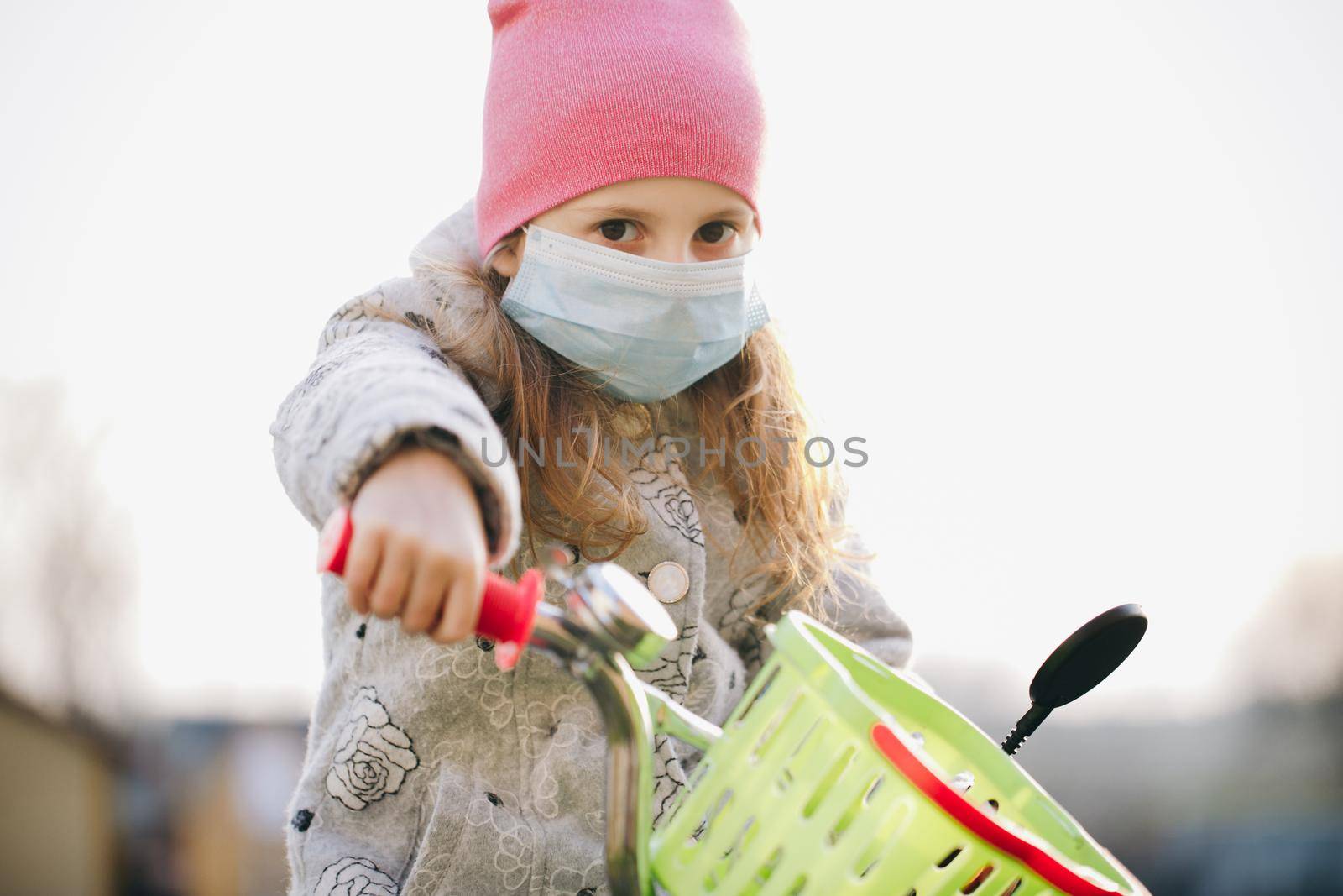 Little Girl Wearing Medical Mask During Coronavirus Epidemic. Sick little girl wearing protection during pandemic. Pretty young Caucasian girl taking on medical mask outdoor by uflypro