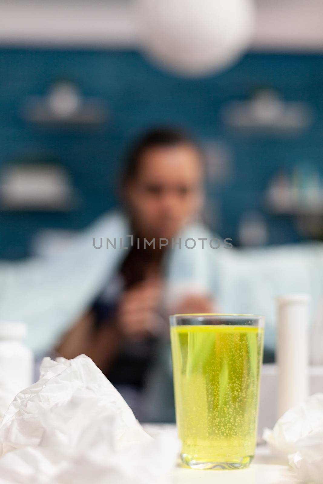 Young woman with illness drinking cup of vitamins by DCStudio