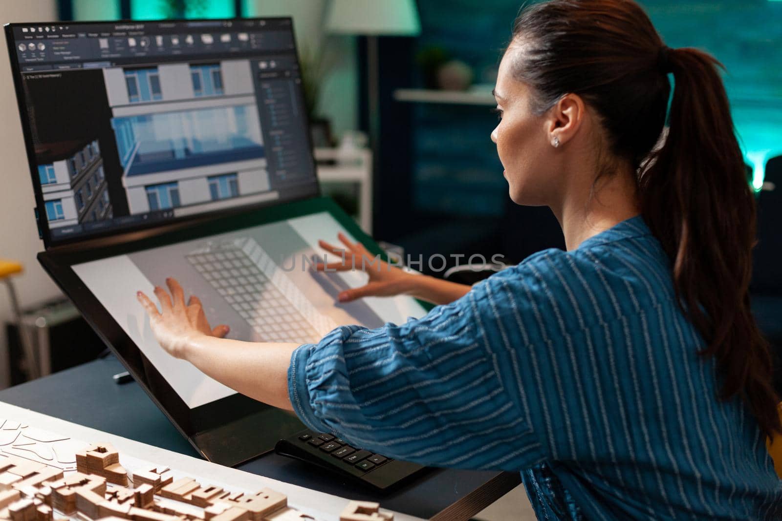 Professional woman architect working on building plan using modern technology equipment touchpad monitor screen computer. Engineer designing virtual sketch for futuristic construction