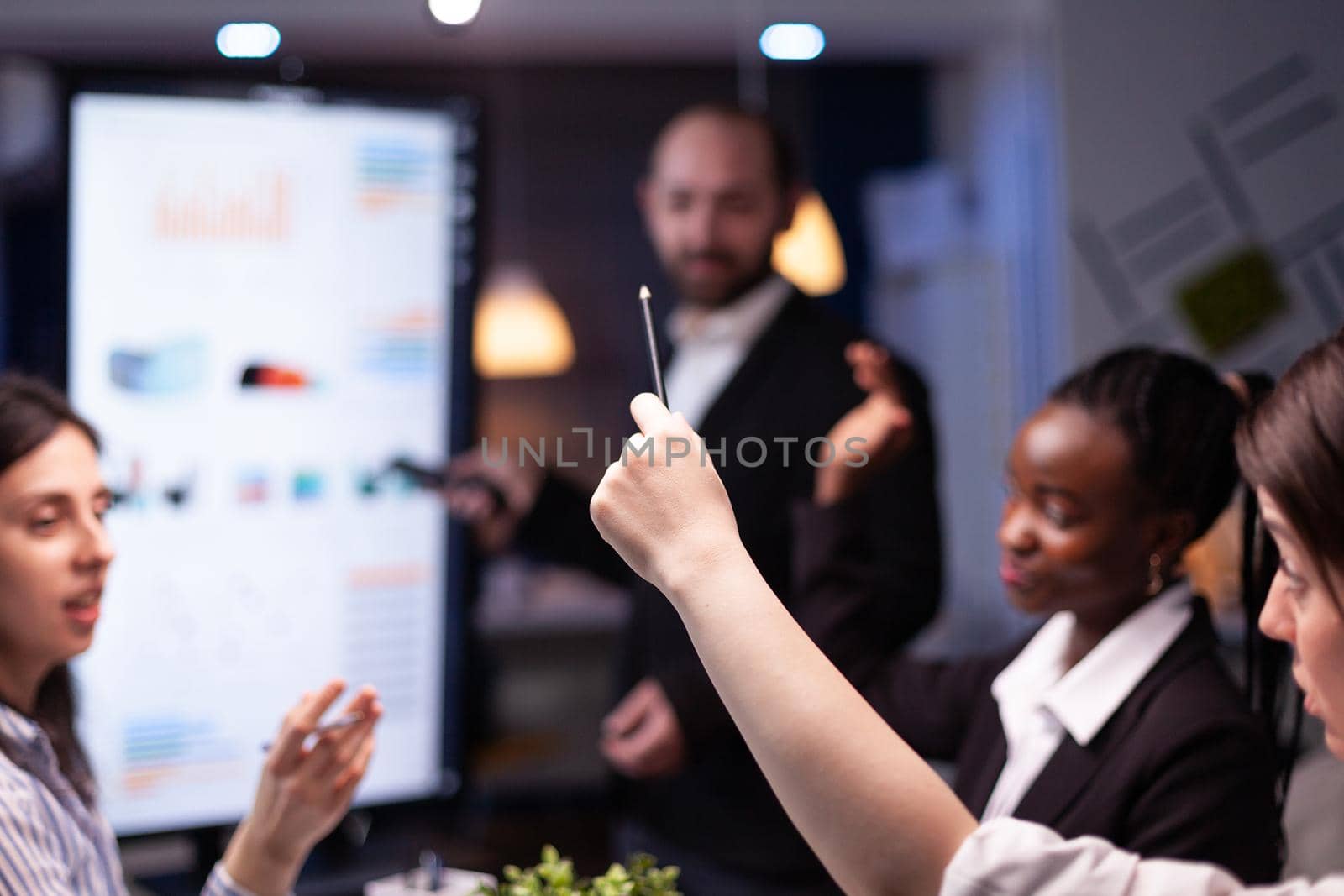 Selective focus of businesswoman leder sitting at desk analyzing marketing presentation discussing financial graps by DCStudio