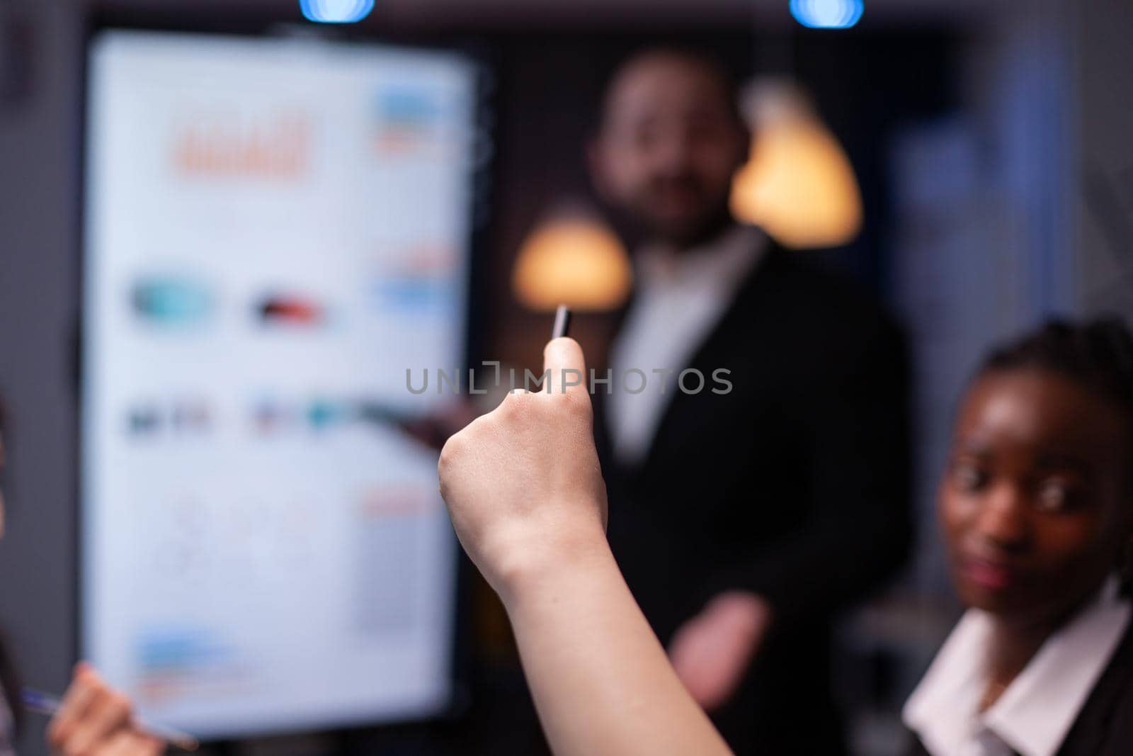 Selective focus of businesswoman asking question during branstorming, late at night in the office. Diverse teamwork working at management presentation in meeting room.