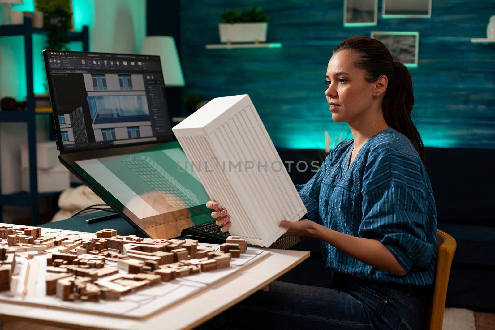 Construction architect holding modern maquette for building planning renovation at project workplace. Technical woman with digital blueprint using computer monitor screen for design
