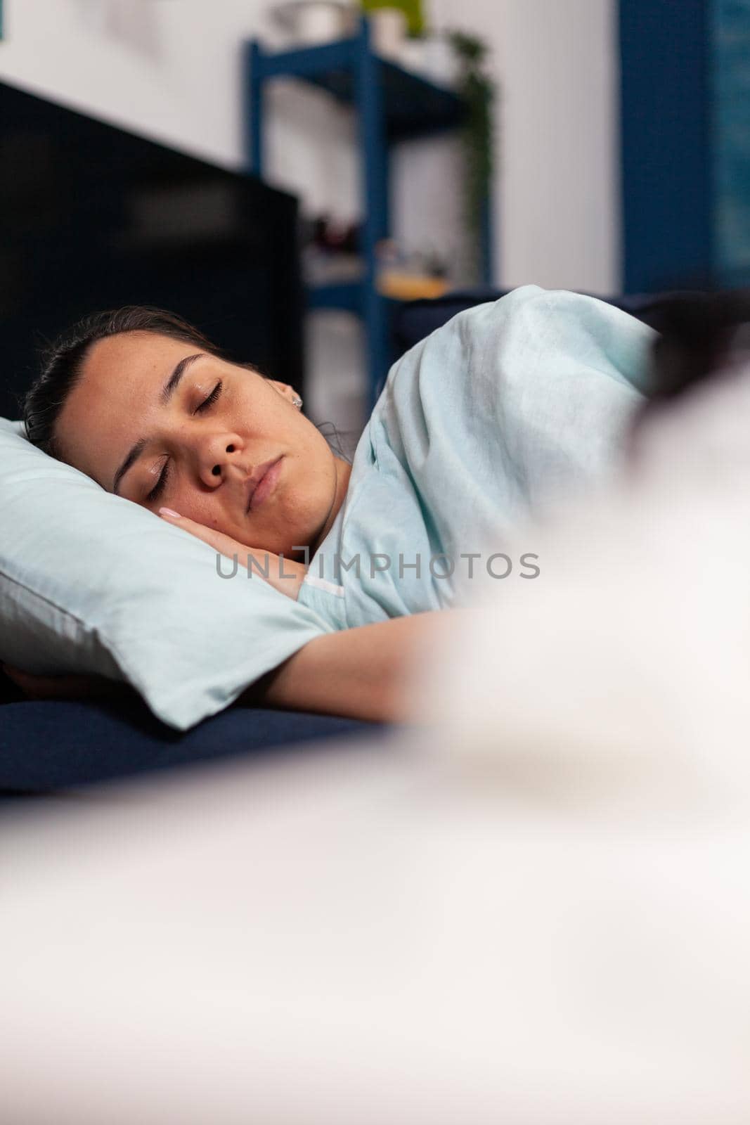 Woman feeling sick sleeping at home on the couch, recovering after cold and flu symptoms. Having fever and taking medicine treatment while resting in bedroom after seasonal disease