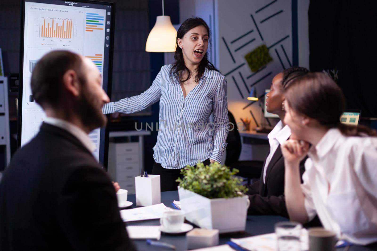 Workaholic focused businesswoman explaining management solution pointing strategy on monitor by DCStudio